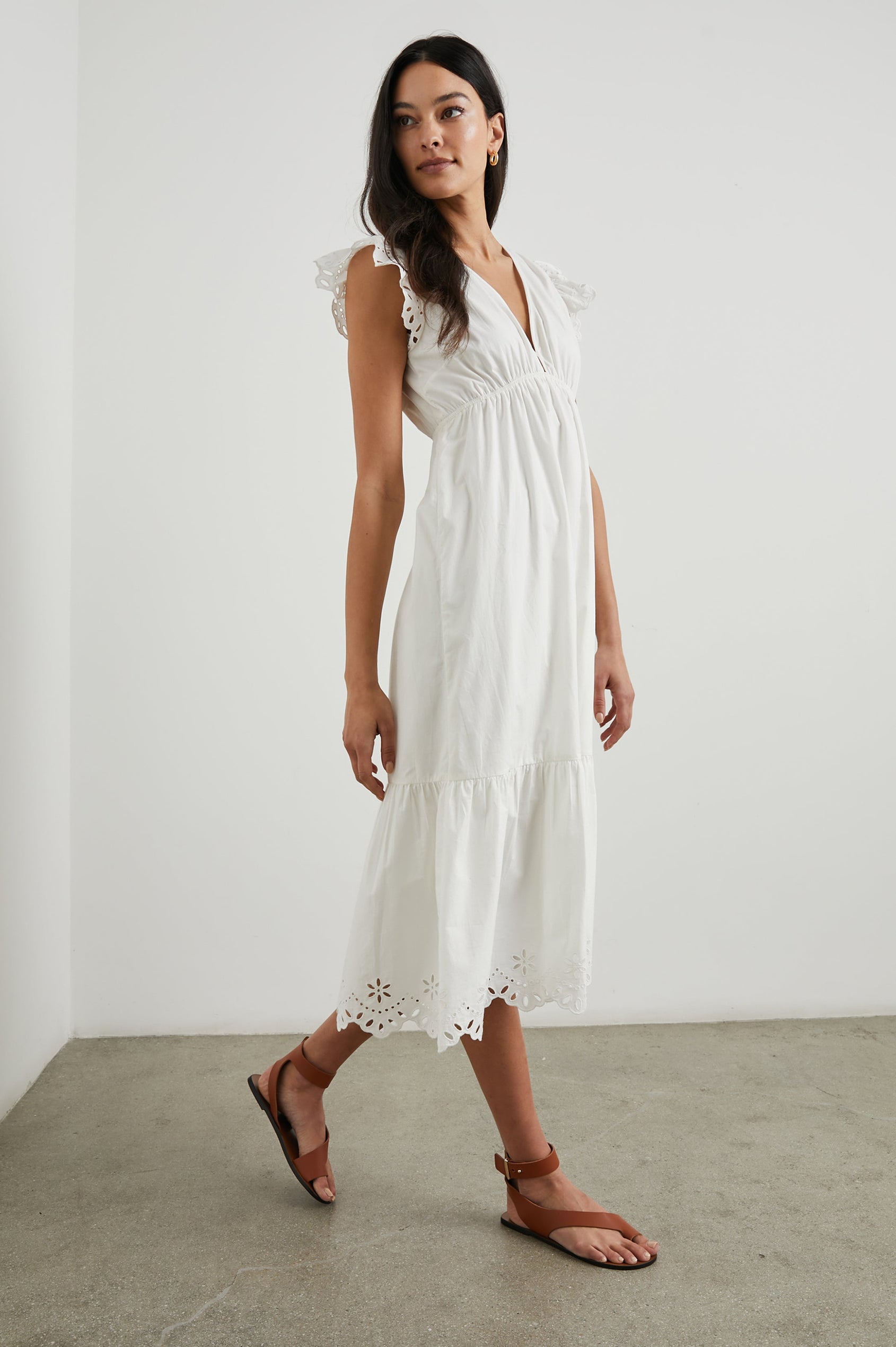 Tina Short Sleeve Midi Dress with Flutter Sleeves, a Deep V Neck with a Cutout and a Tiered Skirt in White Colorway, with eyelets on the Sleeves and an Eyelet Floral Pattern on the Hem - Front Full Body View Featured on Model 