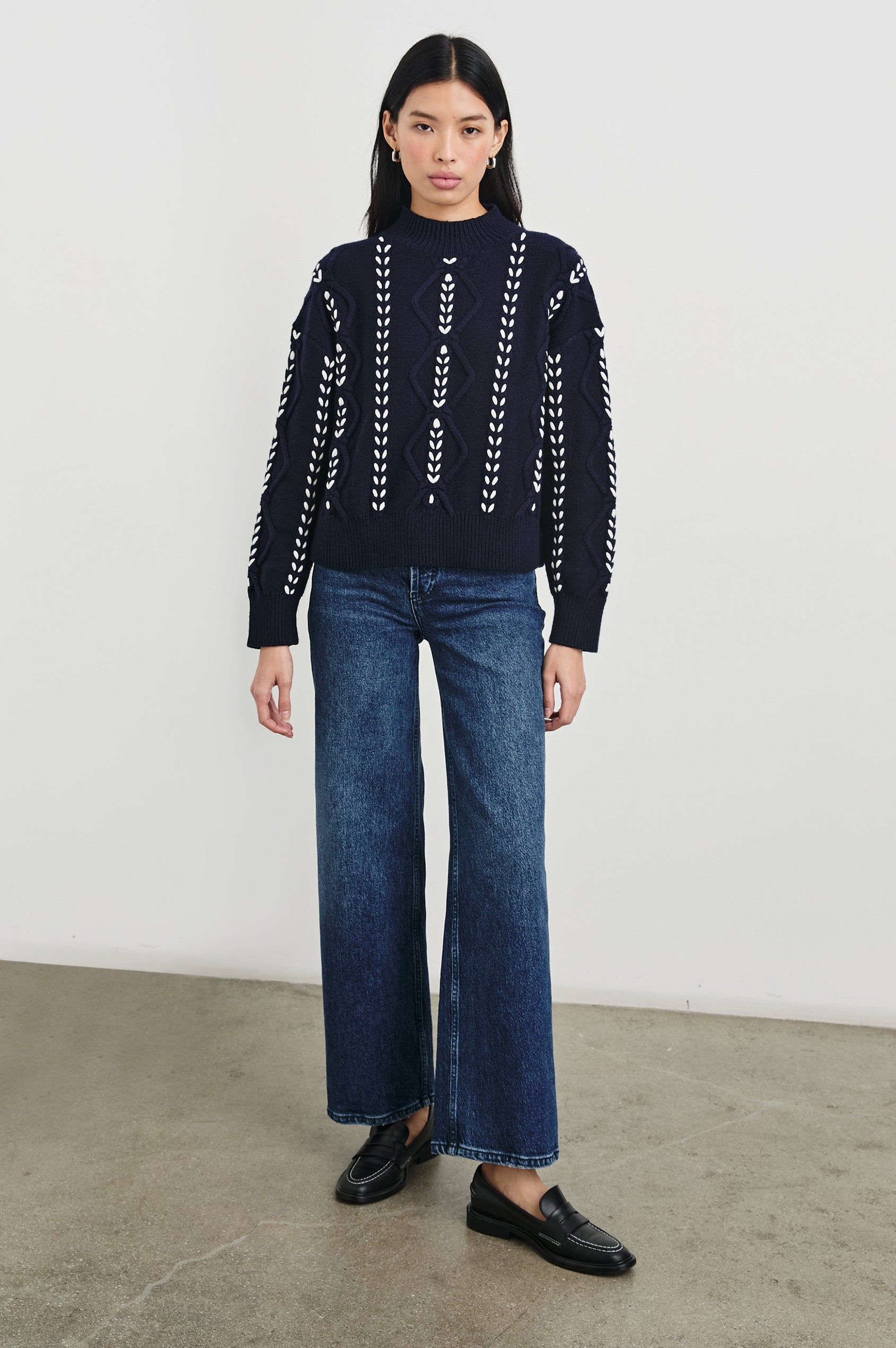 Tori Long-Sleeve Cable Sweater with a Mock Neck, Ribbed Trim in Midnight Colorway, with Thick White Vertical Stitches - Front Full Body View Featured on Model 