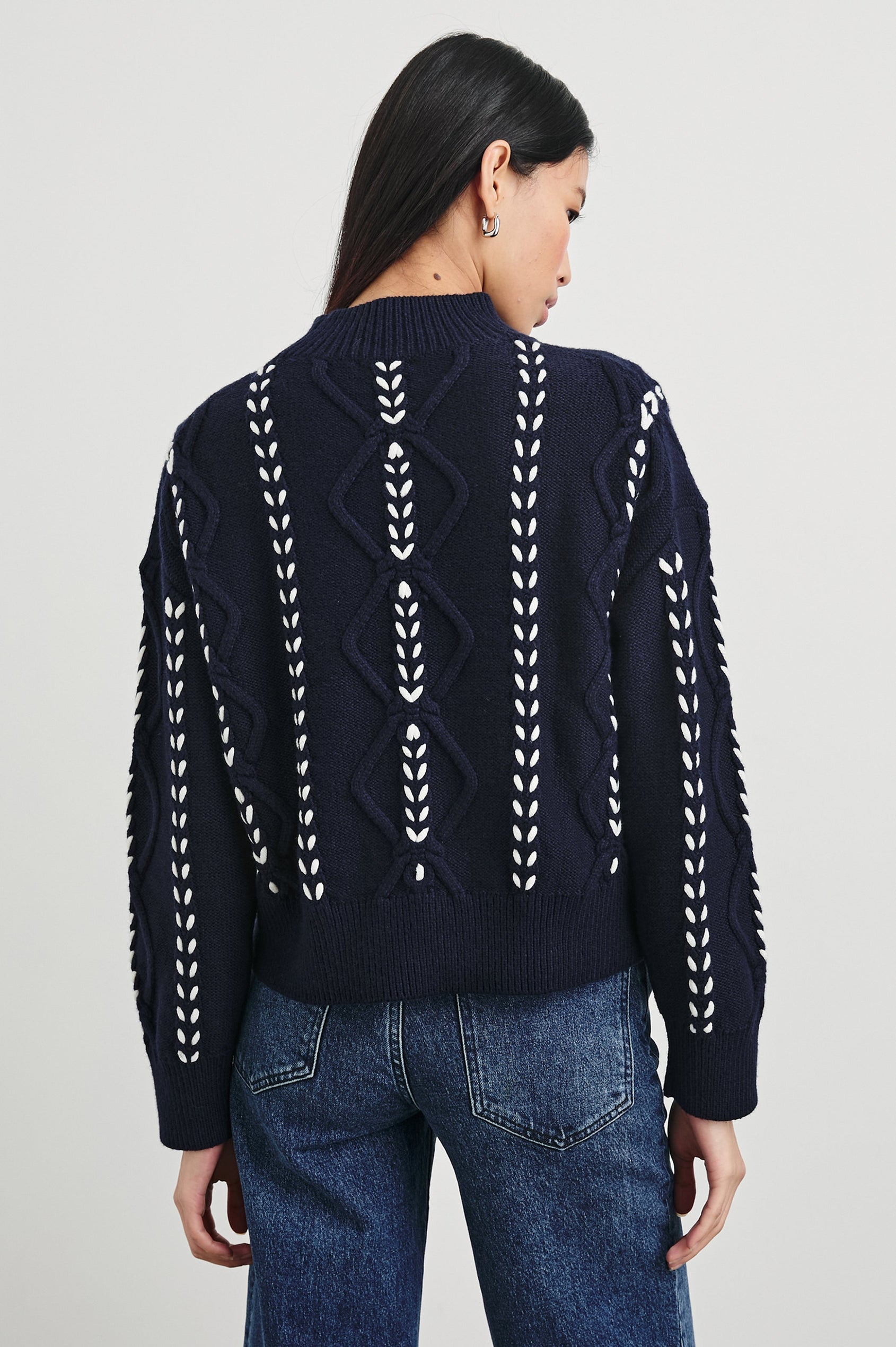 Tori Long-Sleeve Cable Sweater with a Mock Neck, Ribbed Trim in Midnight Colorway, with Thick White Vertical Stitches - Back View Featured on Model 