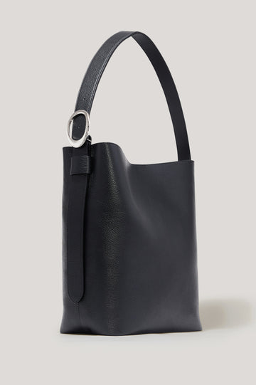 The Torino is a soft pebbled leather bucket bag, designed with an adjustable strap and polished silver oval buckle, in black colorway. Front view featured.