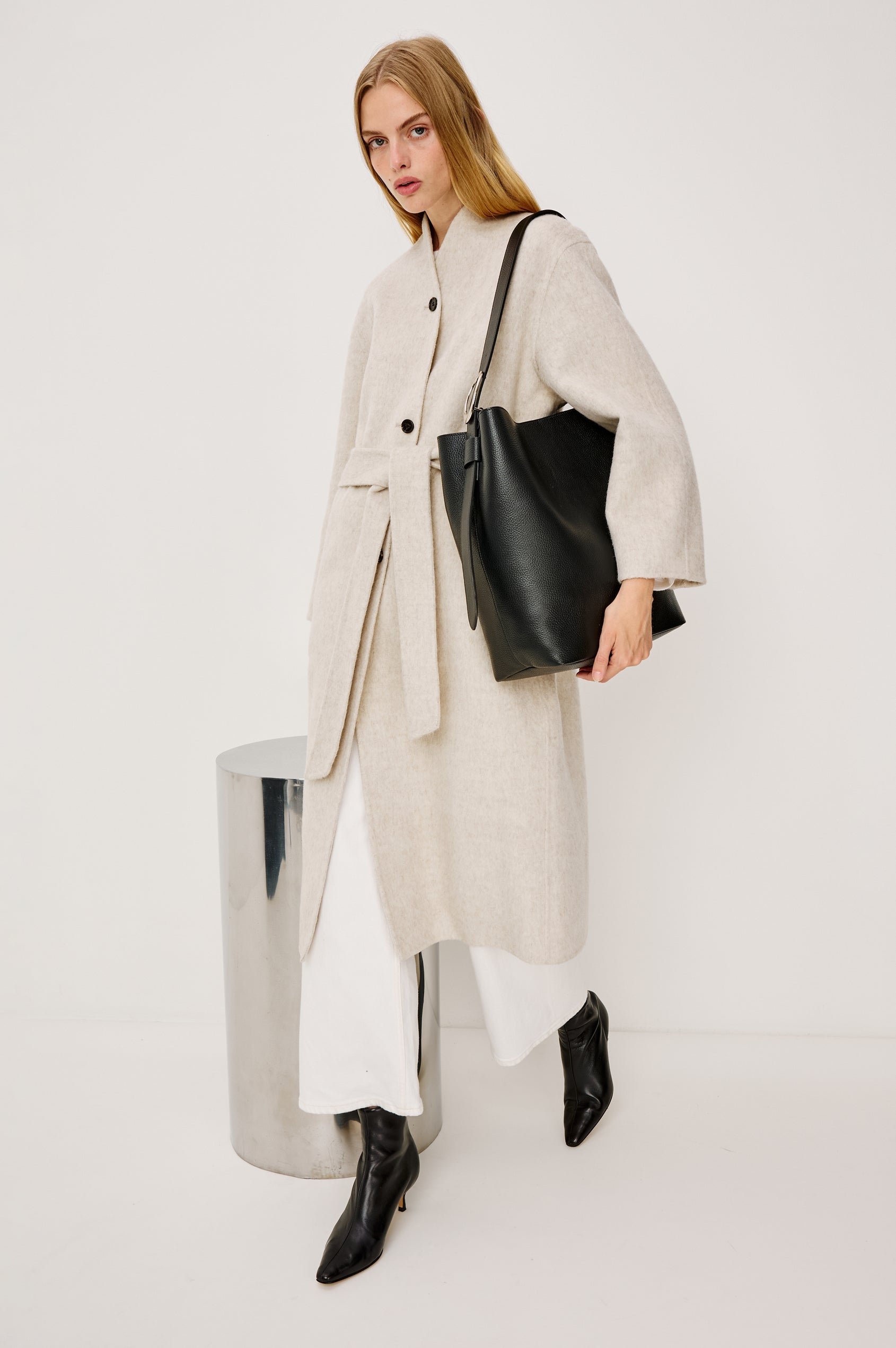 Torino Bucket Bag in Italian Pebbled Leather With Adjustable Strap and Polished Silver Oval Buckle, Microsuede Lining, Interior Magnetic Closure, Snap Button-Slip Pocket, and Subtle Branded Detailing in Black Colorway - Stylized on Model Featured