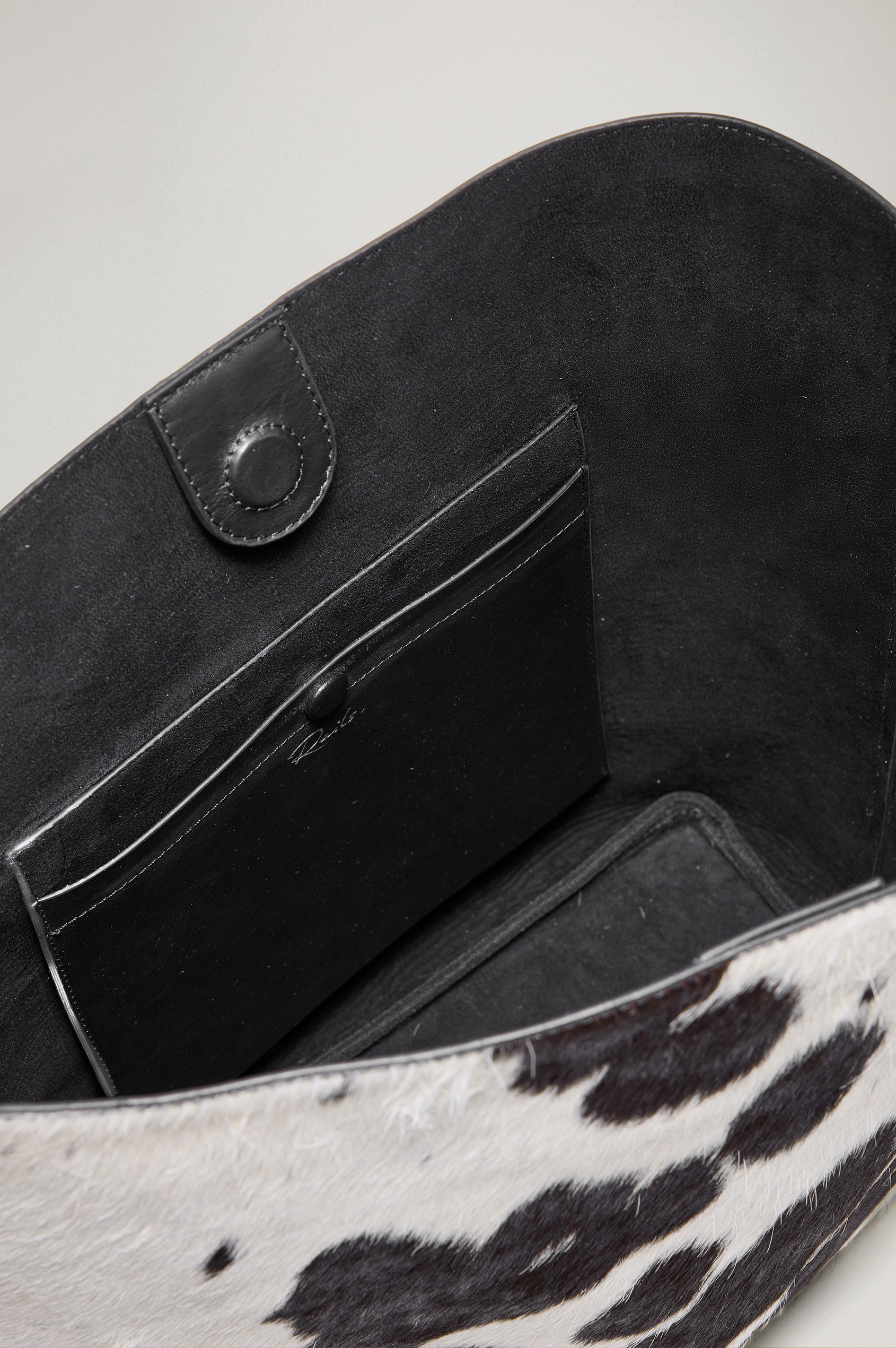 Torino Bucket Bag in Cow Print Haircalf With Adjustable Strap and Polished Silver Oval Buckle, Microsuede Lining, Interior Magnetic Closure, Snap Button-Slip Pocket, and Subtle Branded Detailing in Cowgirl Haircalf Colorway Colorway - Top Interior View Featured