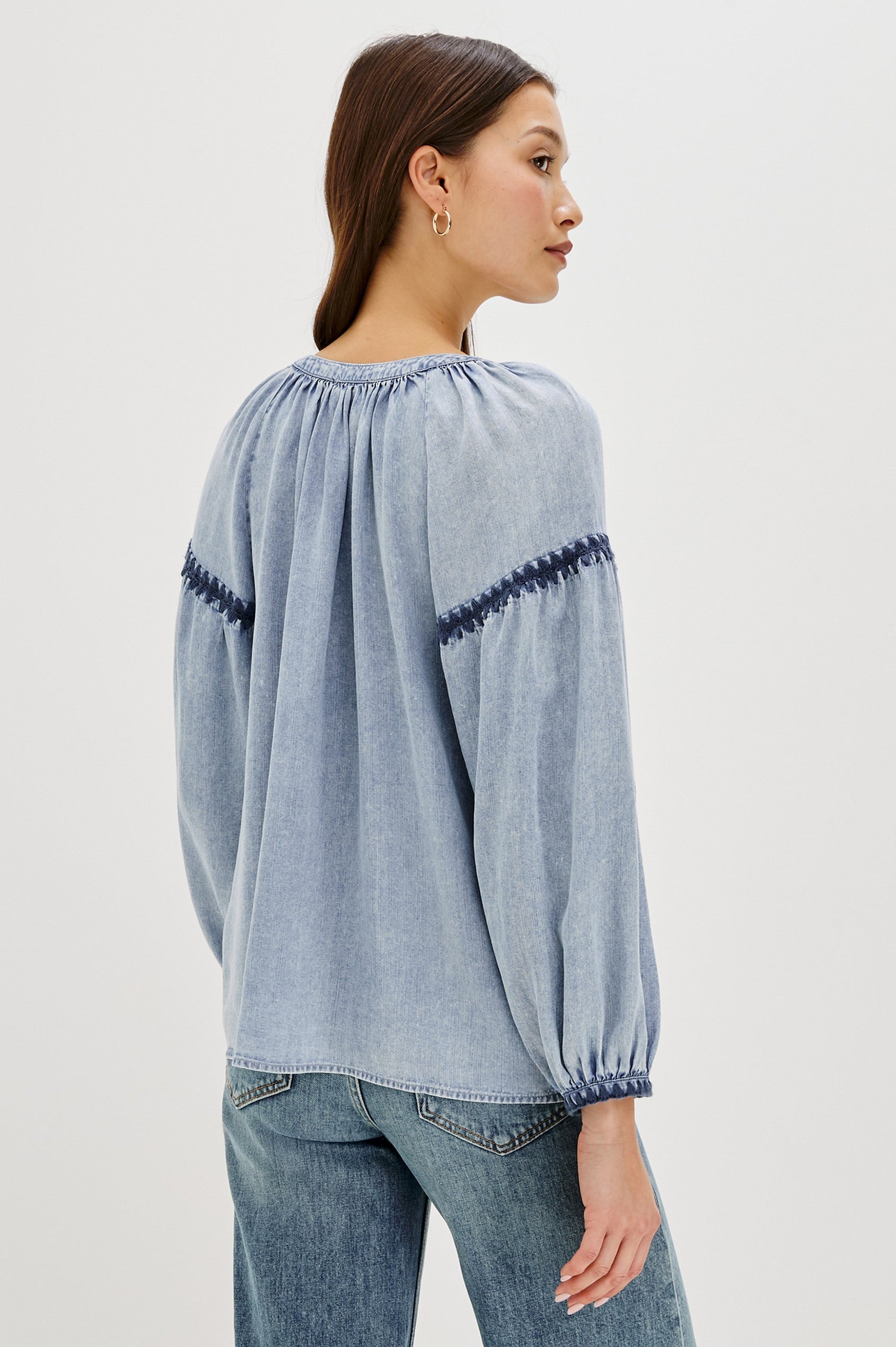 Toshi loose-fitting long sleeve top featuring a v-neckline, front button closure in Medium Cloud Wash Colorway. Contrast blanket stitching at the front, below shoulder sleeve and at the cuff - back view on model