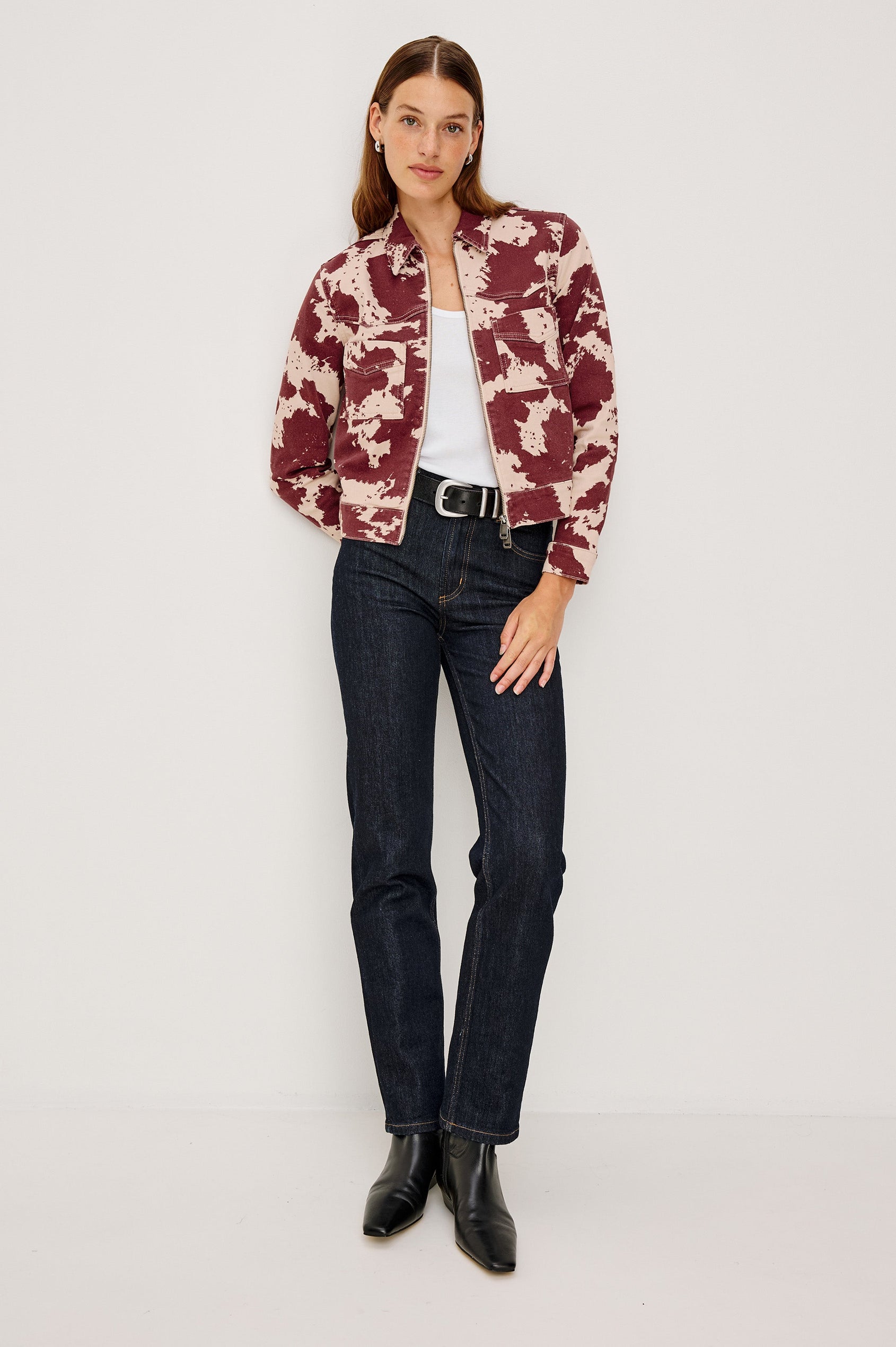 The Trabuco is a collared two-way zip front jacket with two chest pockets and a western style yoke in Cowgirl colorway - a red and beige cow print. Front full body view featured on model.