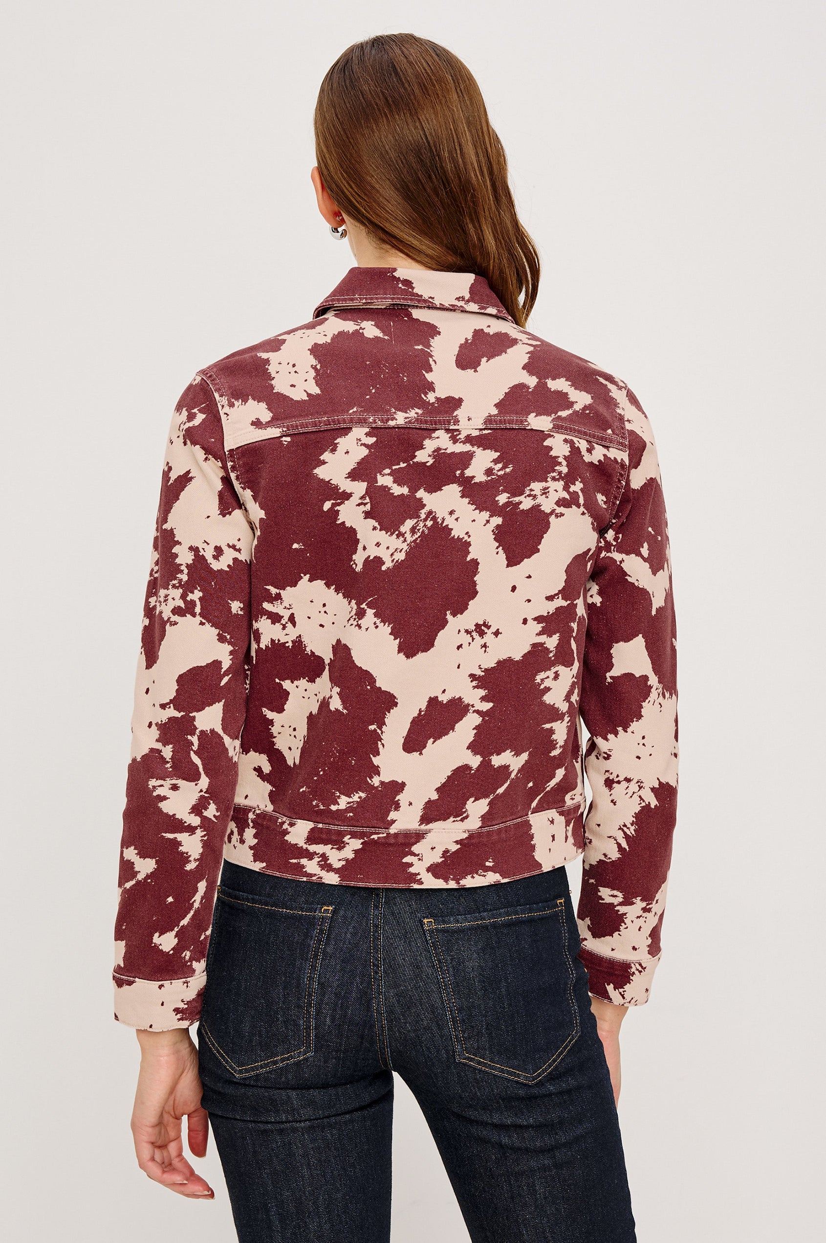 The Trabuco is a collared two-way zip front jacket with two chest pockets and a western style yoke in Cowgirl colorway - a red and beige cow print. Back view featured on model.