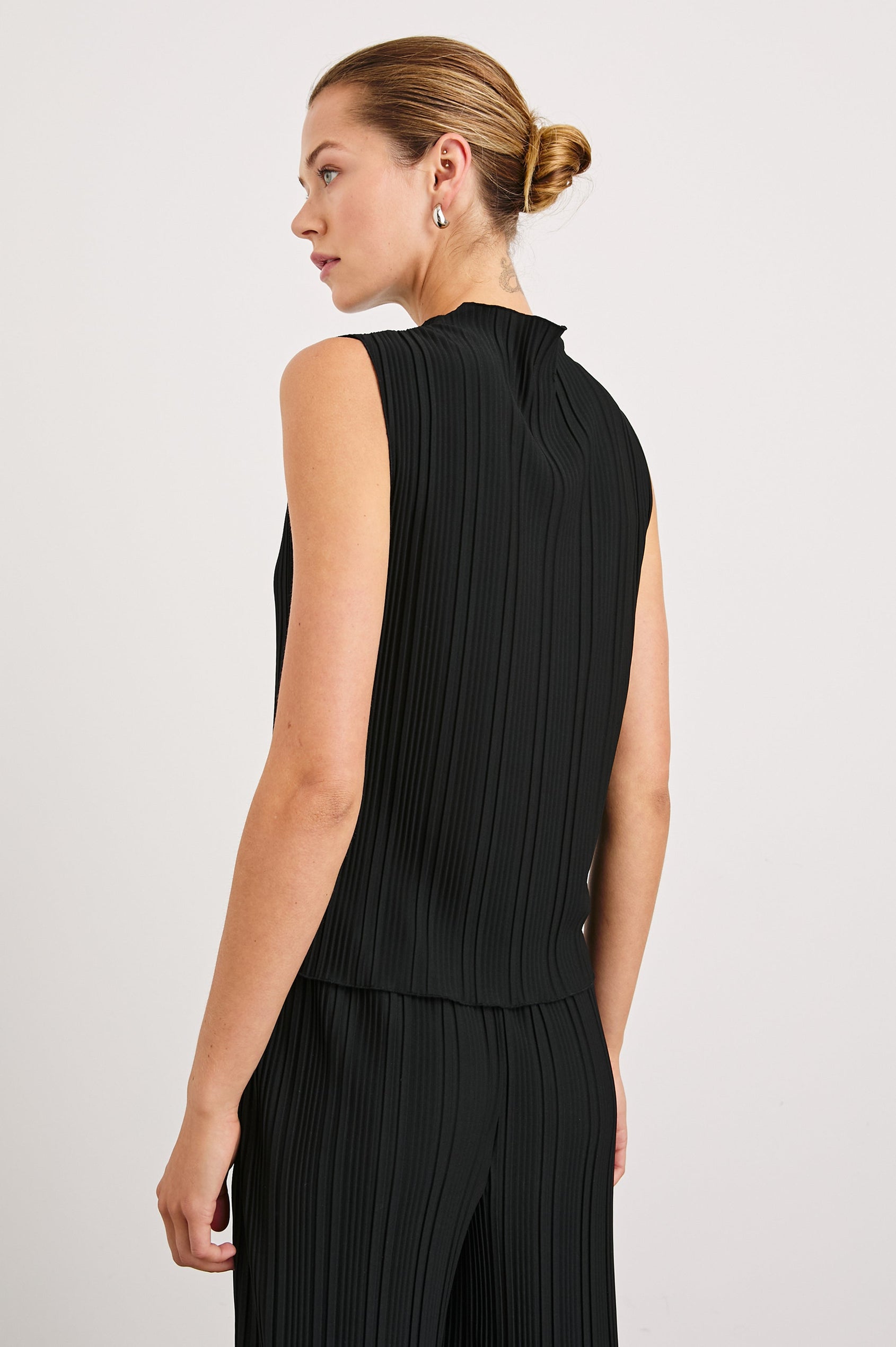 Trea Sleeveless Top with a Mock Neck and Pleated Texture in Jet Colorway - Back View Featured on Model