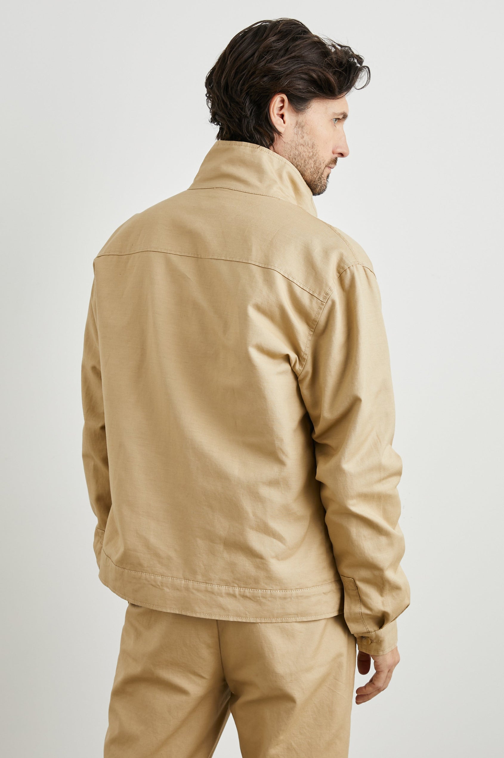 Tyrell Jacket with Button Closure, Two Front Pockets, Two Chest Buttoned Flap Pockets, and a Stand Collar in Khaki Colorway - Back View Featured on Model