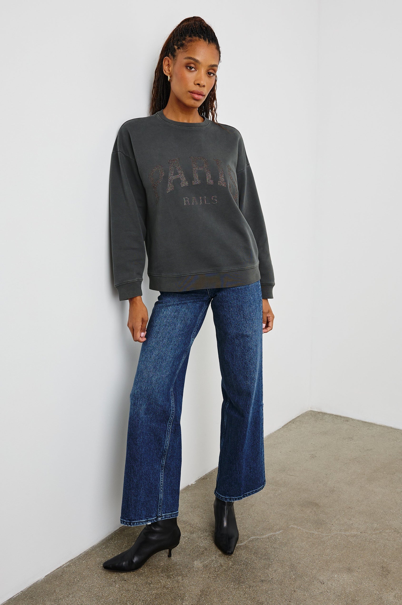 The Varsity Sweatshirt with a Crew Neck and Glitter Text states, Paris Rails in Paris Glitter Colorway, on dark grey - Front Full Body View Featured on Model 