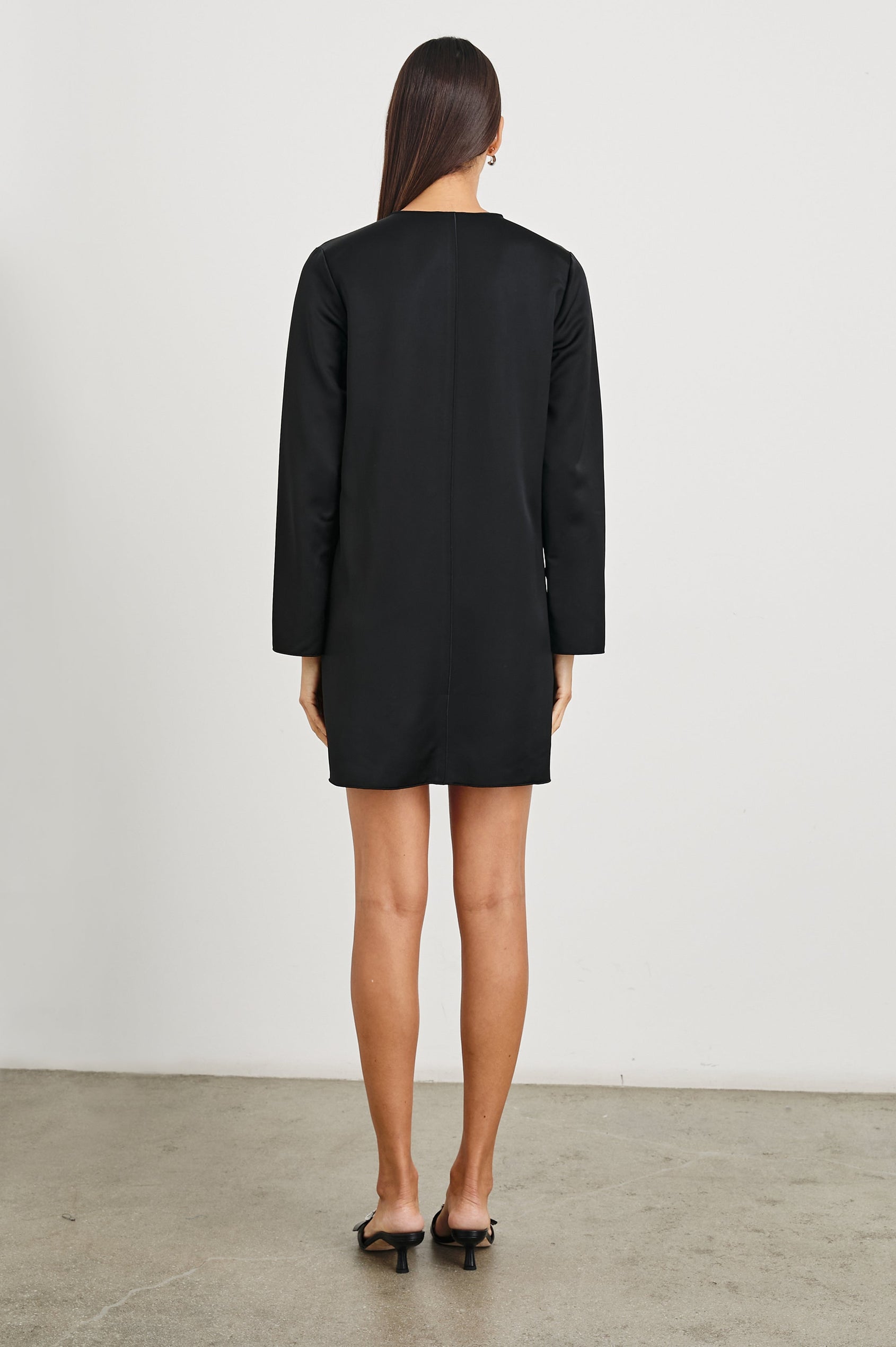 Victoria Long-Sleeve Mini Dress with a V Neck, and Front and Back Center Vertical Seams in Black Colorway - Back Full Body View Featured on Model 