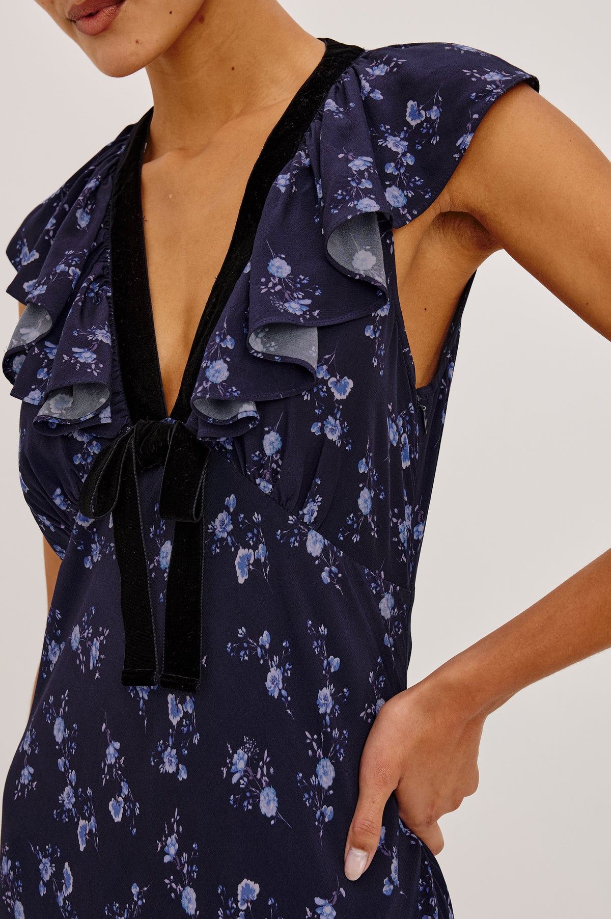 Virginia Maxi Dress in Lightweight Crepe With Ruffle-Trimmed Plunging V-Neckline With Center-Front Bow, Bias Cut, Side Zip Closure, and Godet Insets in Navy Romantic Floral Colorway - Upper Body Front Detail View Featured on Model.