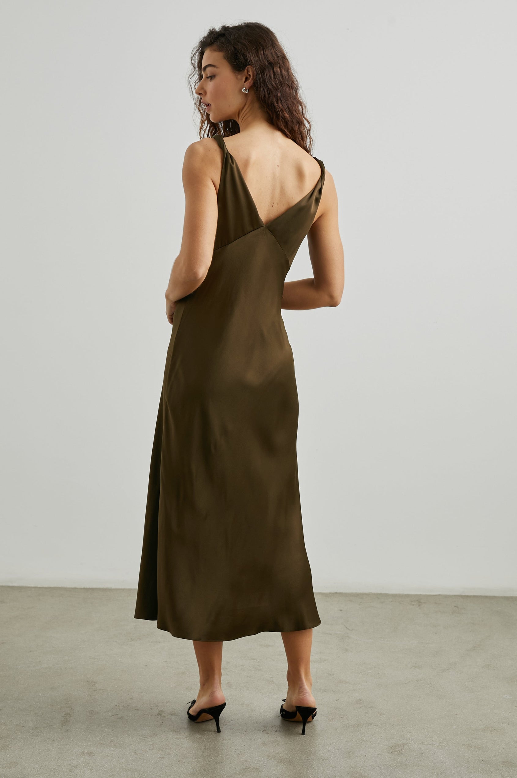 Viviana Sleeveless Midi Dress with a Deep V Neck that Extends into a Twist, Twisted Shoulder Straps, and a Center Slit in Dark Moss Colorway - Back Full Body View Featured on Model  