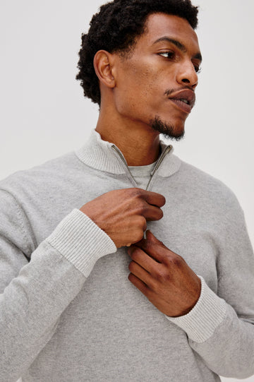 The Waylon is a quarter zip mock neck sweater with long sleeves and rib trim in Grey Heather colorway. Front detail view featured on model.