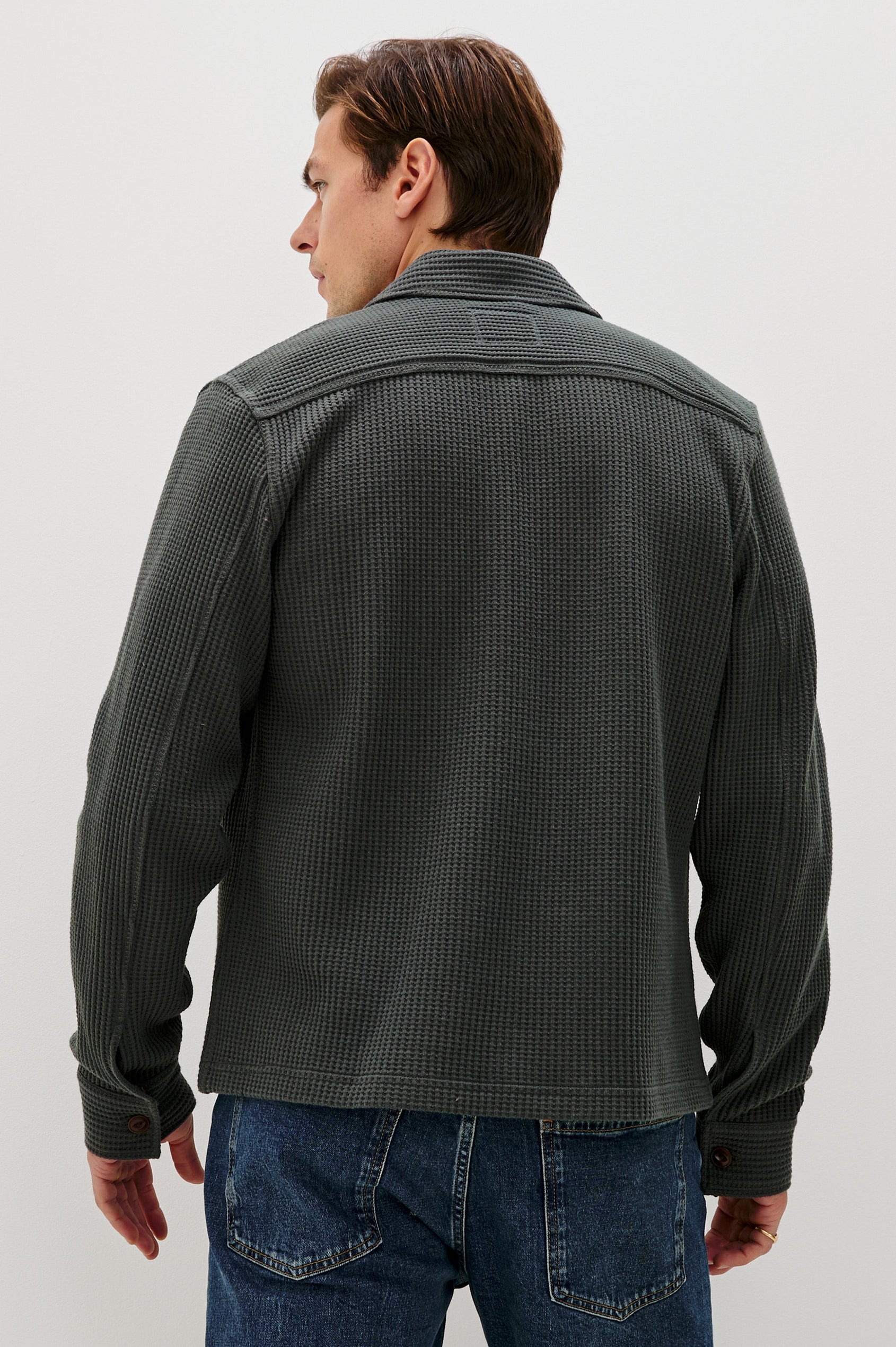 The Wells is a collared button front shirt jacket with contrast brown buttons and two chest pockets in Ink colorway. Back view featured on model.