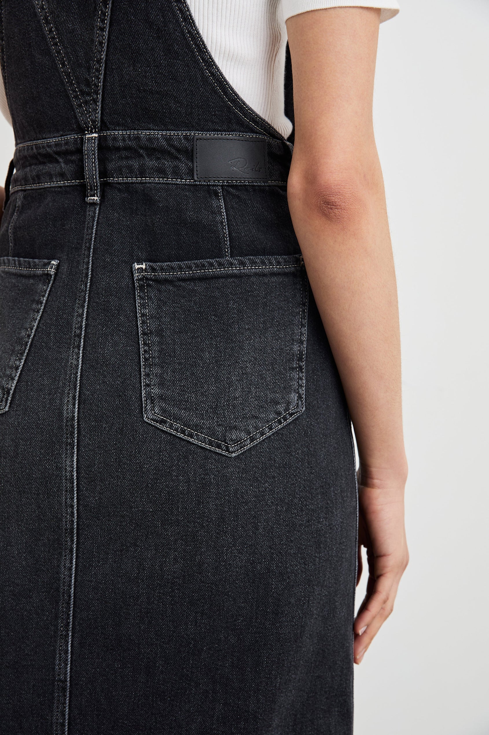 Westlake Midi Denim Dress with an Overalls-Style Bodice, Two Front Pockets, a Bib Chest Patch Pocket, Two Back Patch Pockets, Belt Loops and a Center Slit in Black Sand Colorway - Back View Featured on Model