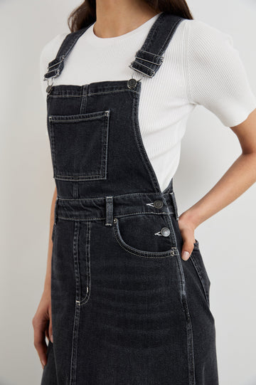 Westlake Midi Denim Dress with an Overalls-Style Bodice, Two Front Pockets, a Bib Chest Patch Pocket, Two Back Patch Pockets, Belt Loops and a Center Slit in Black Sand Colorway - Front View Featured on Model