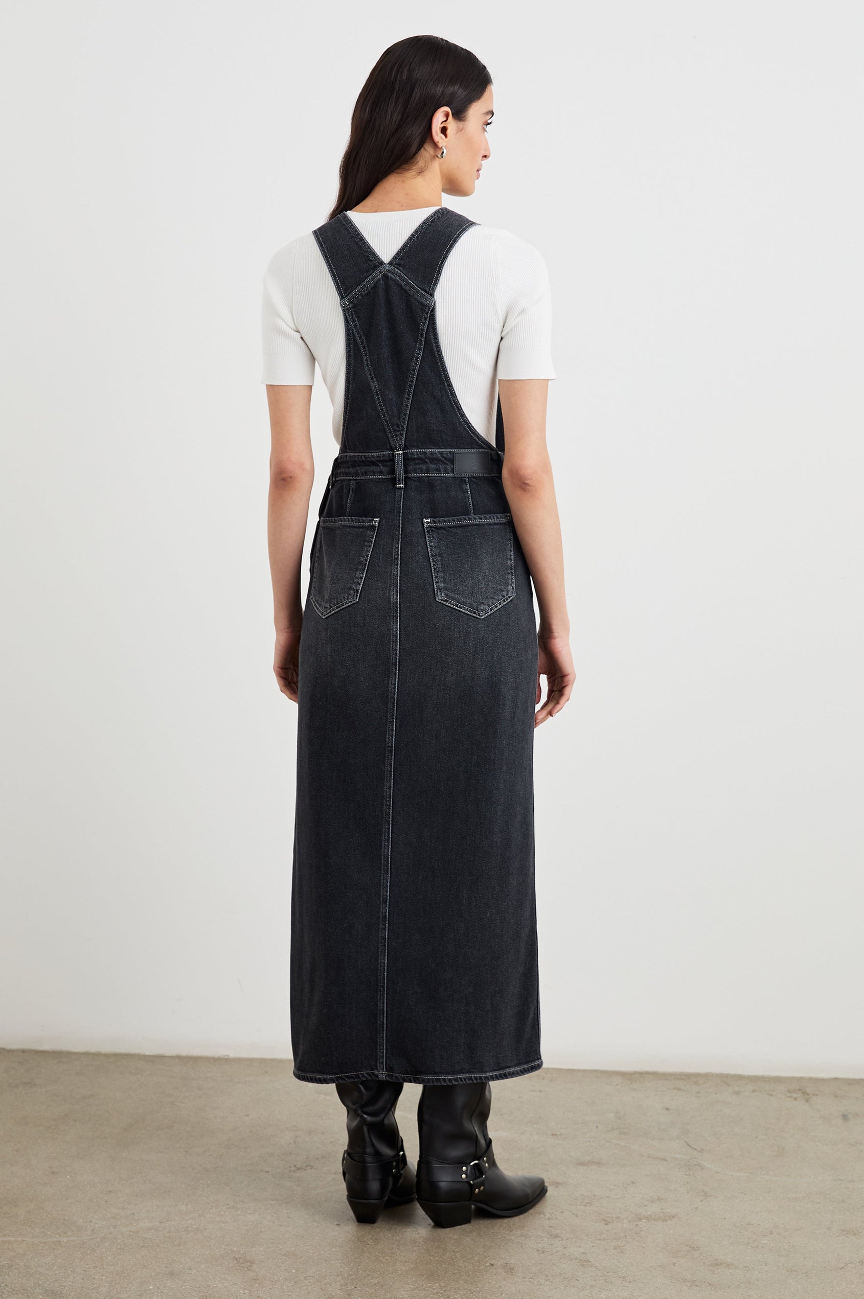 Westlake Midi Denim Dress with an Overalls-Style Bodice, Two Front Pockets, a Bib Chest Patch Pocket, Two Back Patch Pockets, Belt Loops and a Center Slit in Black Sand Colorway - Back Full Body View Featured on Model