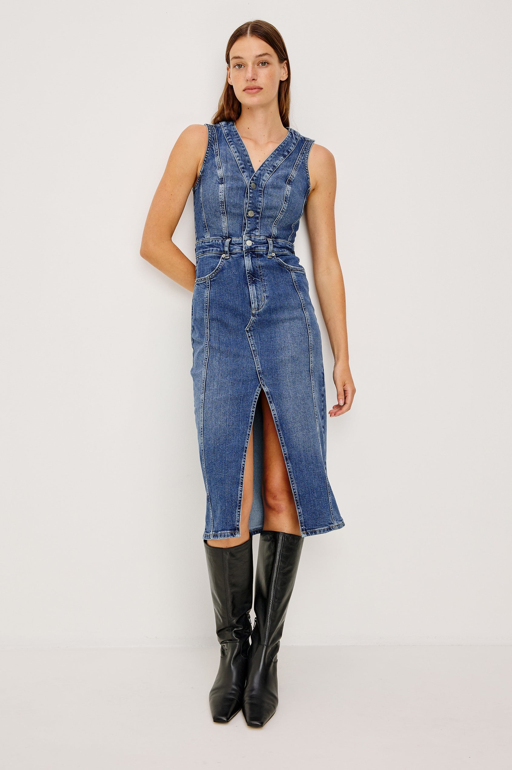 Westwood Sleeveless Denim Midi Dress with Belt Loops, a Button and Zipper Closure for the Skirt and Button Closure on the Bodice, a V neck, a Front Center Thigh Slit, Two Front Pockets  and Two Back Patch Pockets in Forget Me Not Colorway, a Blue - Front View Featured on Model