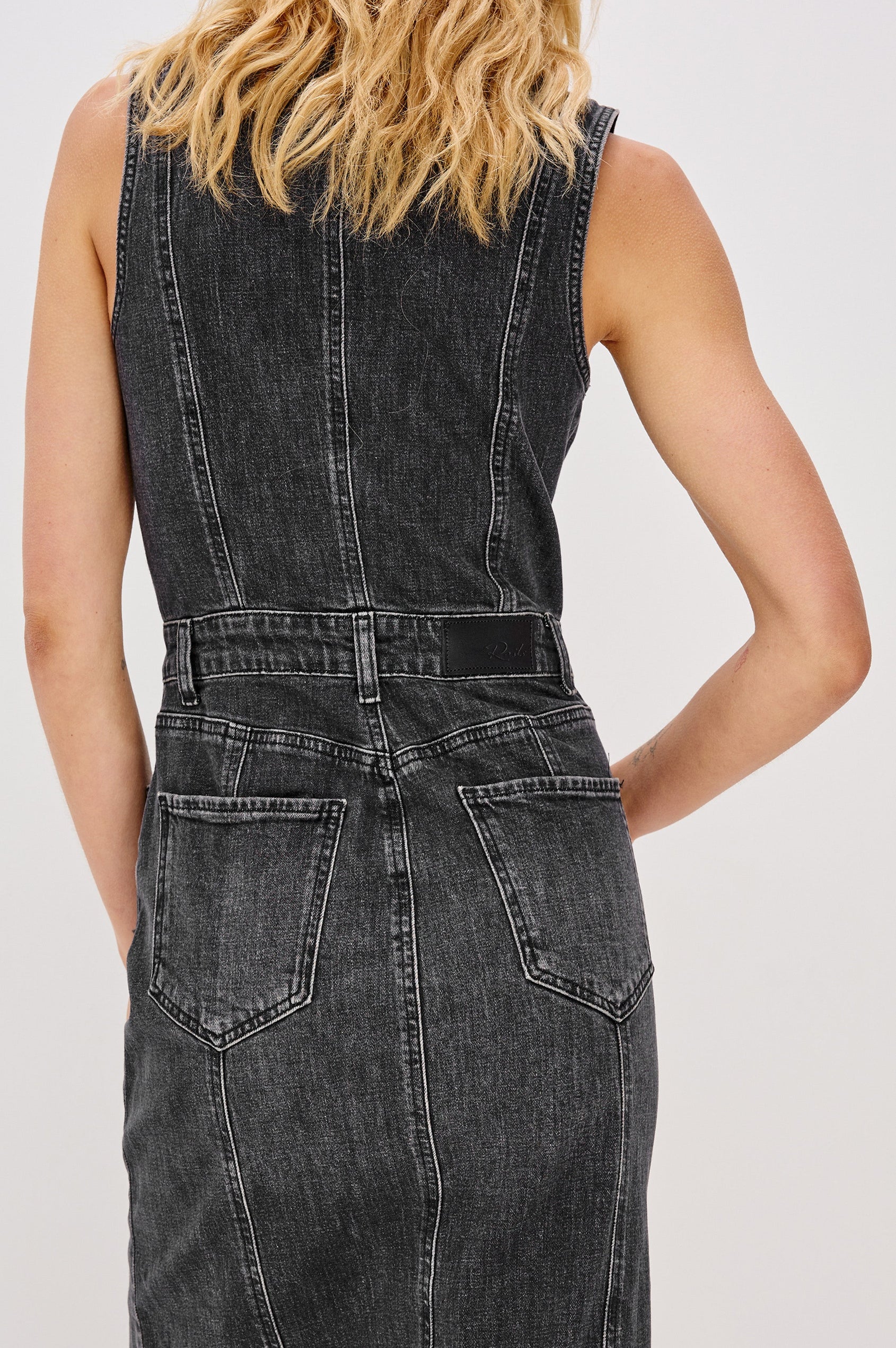 Westwood Sleeveless Denim Midi Dress with Belt Loops, a Button and Zipper Closure for the Skirt and Button Closure on the Bodice, a V neck, a Front Center Thigh Slit, Two Front Pockets  and Two Back Patch Pockets in Black Pearl Colorway, a washed black- Back View Featured on Model
