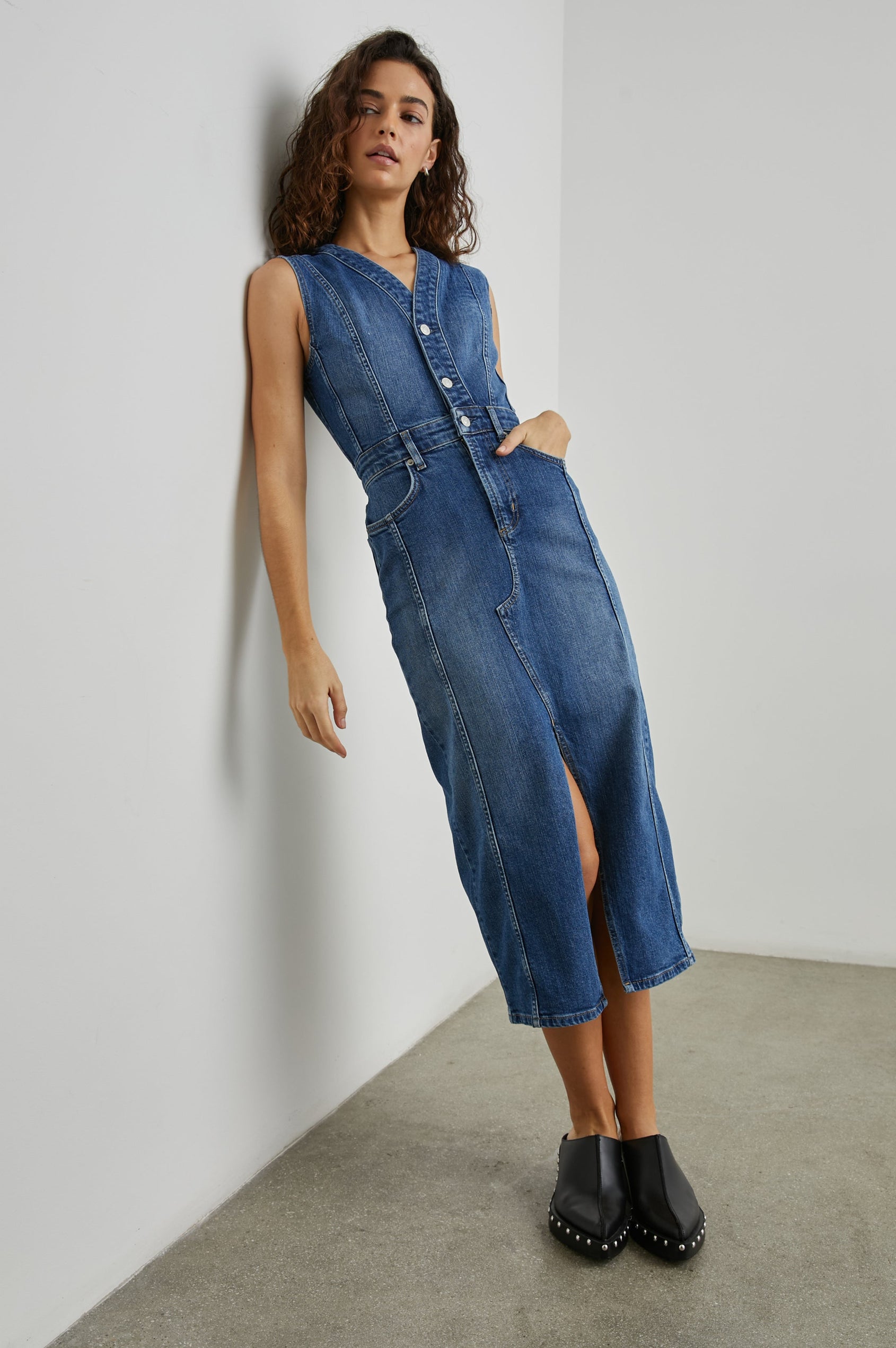 Westwood Sleeveless Denim Midi Dress with Belt Loops, a Button and Zipper Closure for the Skirt and Button Closure on the Bodice, a V neck, a Front Center Thigh Slit, Two Front Pockets  and Two Back Patch Pockets in Forget Me Not Colorway, a Blue - Front Full Body View Featured on Model