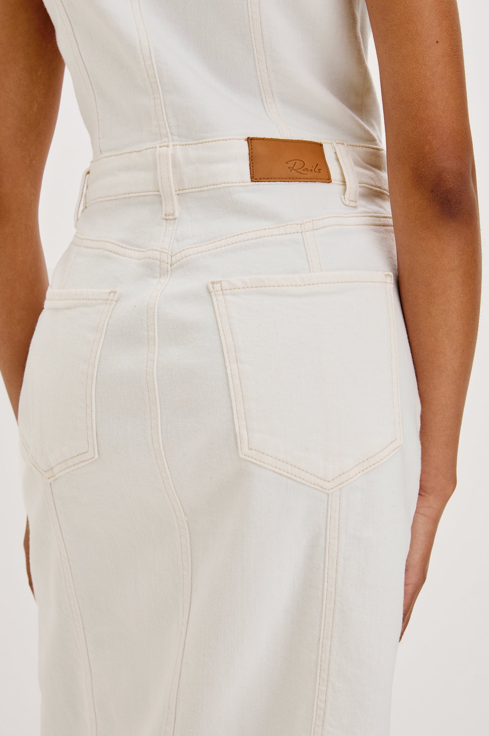 Westwood Sleeveless Denim Midi Dress with Belt Loops, a Button and Zipper Closure for the Skirt and Button Closure on the Bodice, a V neck, a Front Center Thigh Slit, Two Front Pockets  and Two Back Patch Pockets in Vintage Ecru Colorway - close up of back details on model