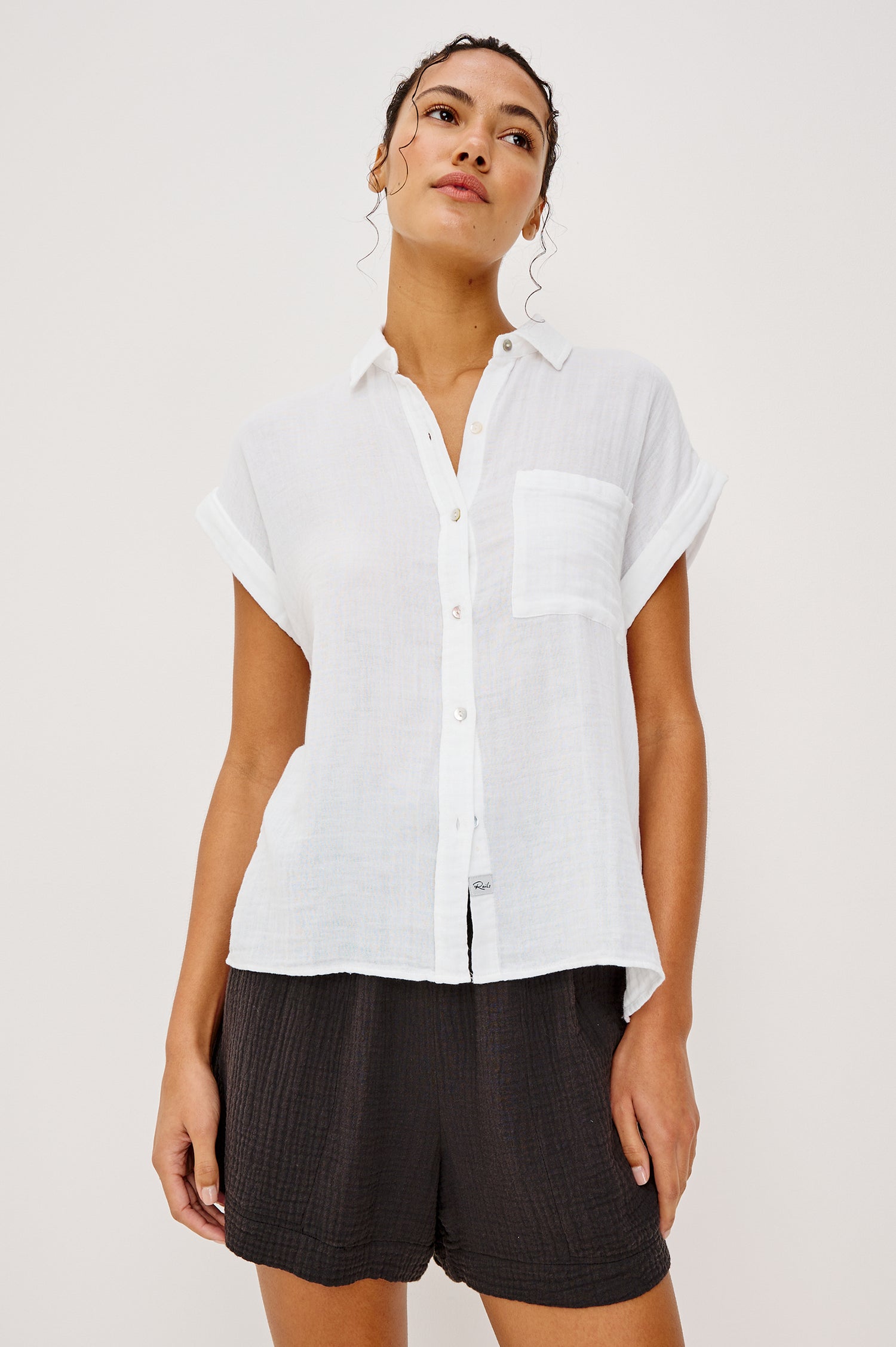 Whitney button front collared shirt with cuffed cap sleeve, features a chest pocket in white colorway. Front view featured on model
