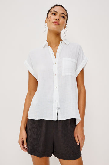 Whitney button front collared shirt with cuffed cap sleeve, features a chest pocket in white colorway. Front view featured on model