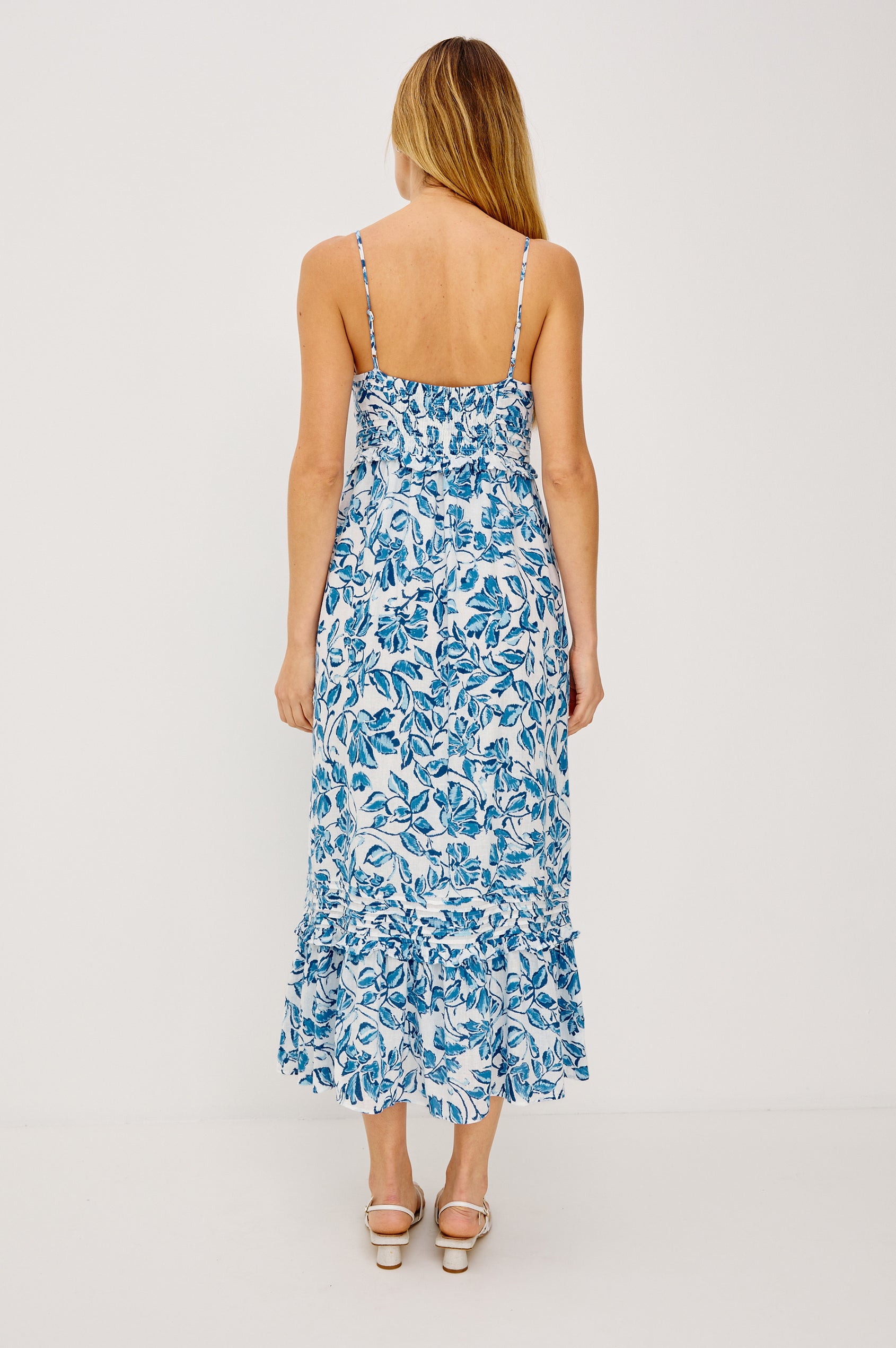 Wisteria Midi Dress in Luxe Linen With V-Neckline, Adjustable Shoulder Straps, Front Buttons, Seam and Ruffle Detailing, Relaxed Fit, and Smocked Back in Azure Jasmine Colorway - Full Body Back View Featured on Model