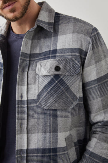 Worthing Jacket with Button Closure and two Chest Button Flap Pockets in Slate Mist Heather Colorway, a Grey and Blue Plaid - Front View Featured on Model