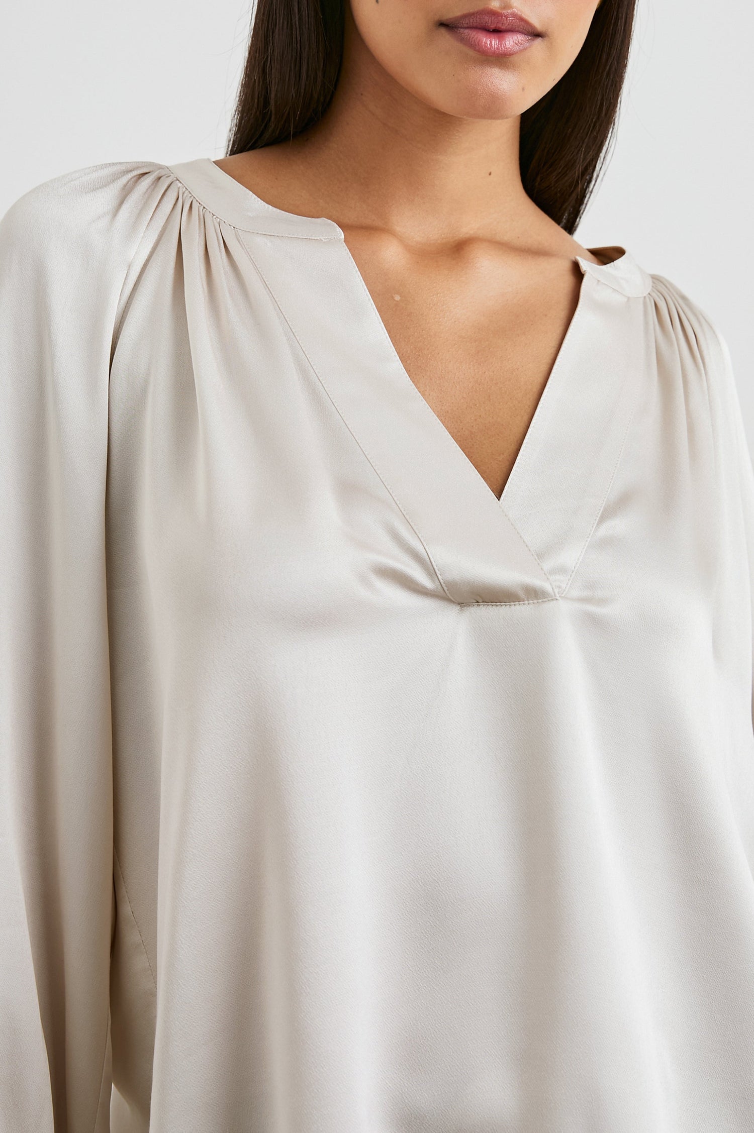 Wynna Long-Sleeve Top with a Deep V Neck and Ruching above the Cuffs and at the Neckline in Ivory Colorway - Front View Featured on Model