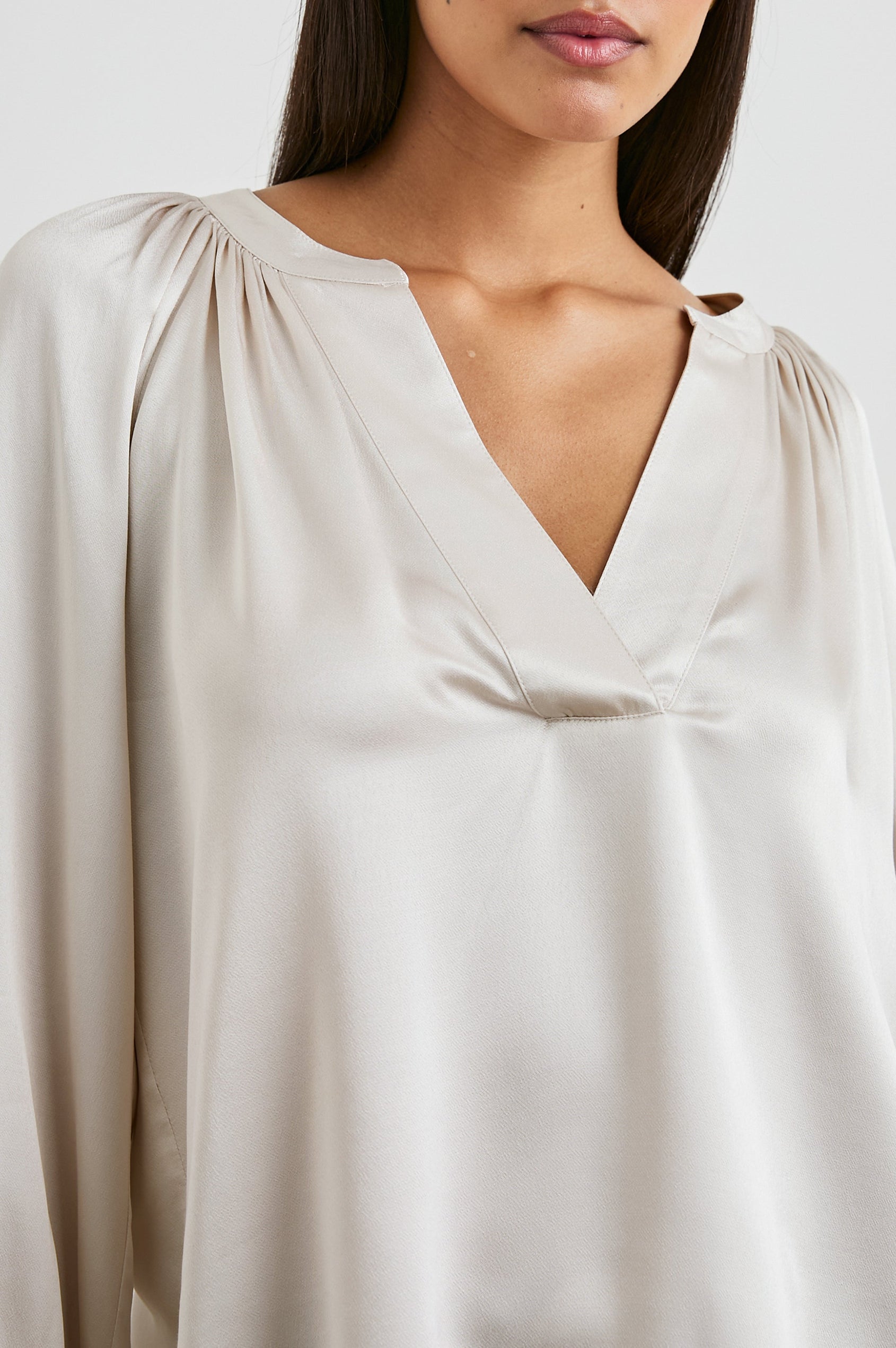 Wynna Long-Sleeve Top with a Deep V Neck and Ruching above the Cuffs and at the Neckline in Ivory Colorway - Front View Featured on Model