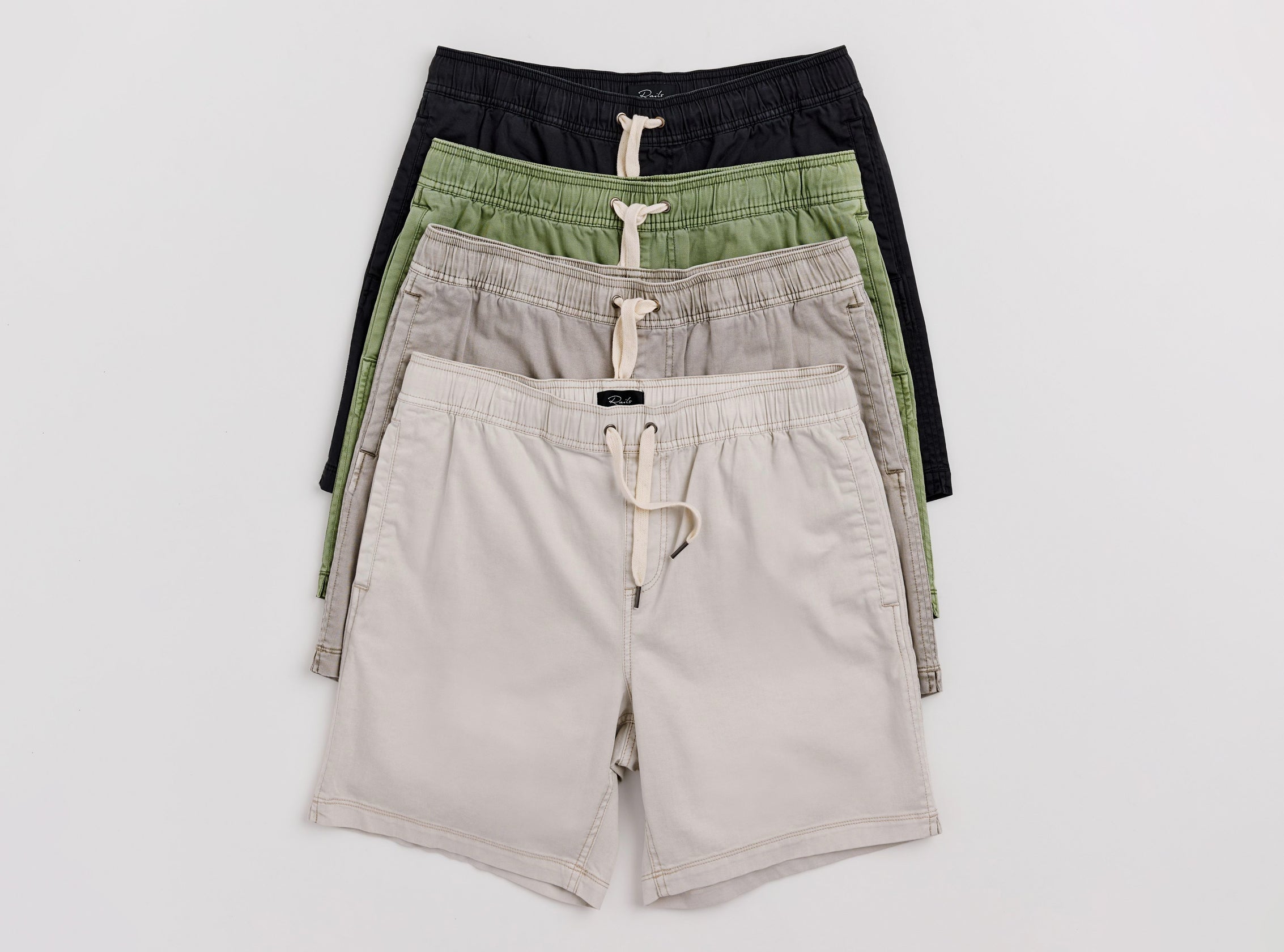 Four pairs of shorts in black, green, and beige on a white background