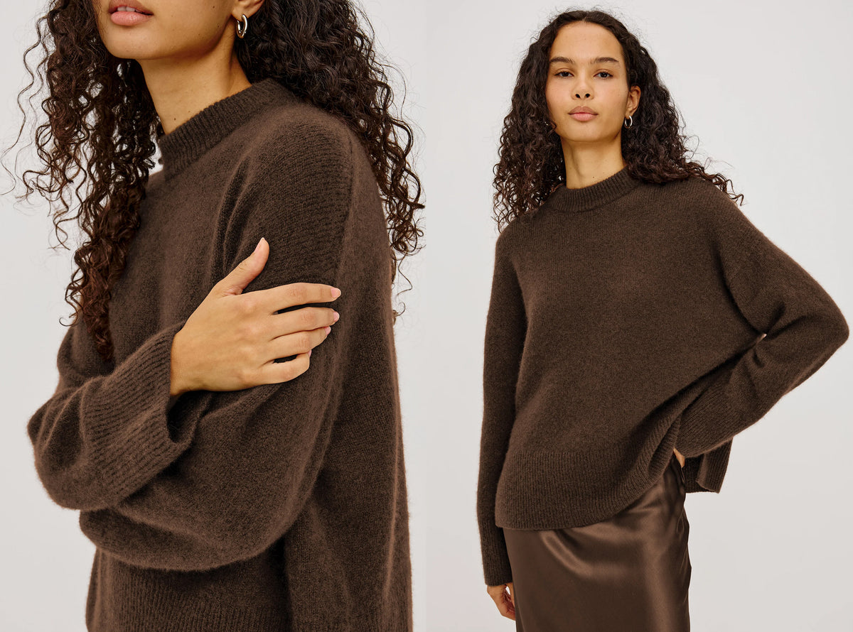 Woman wearing a brown cashmere sweater with a brown skirt against a white background.