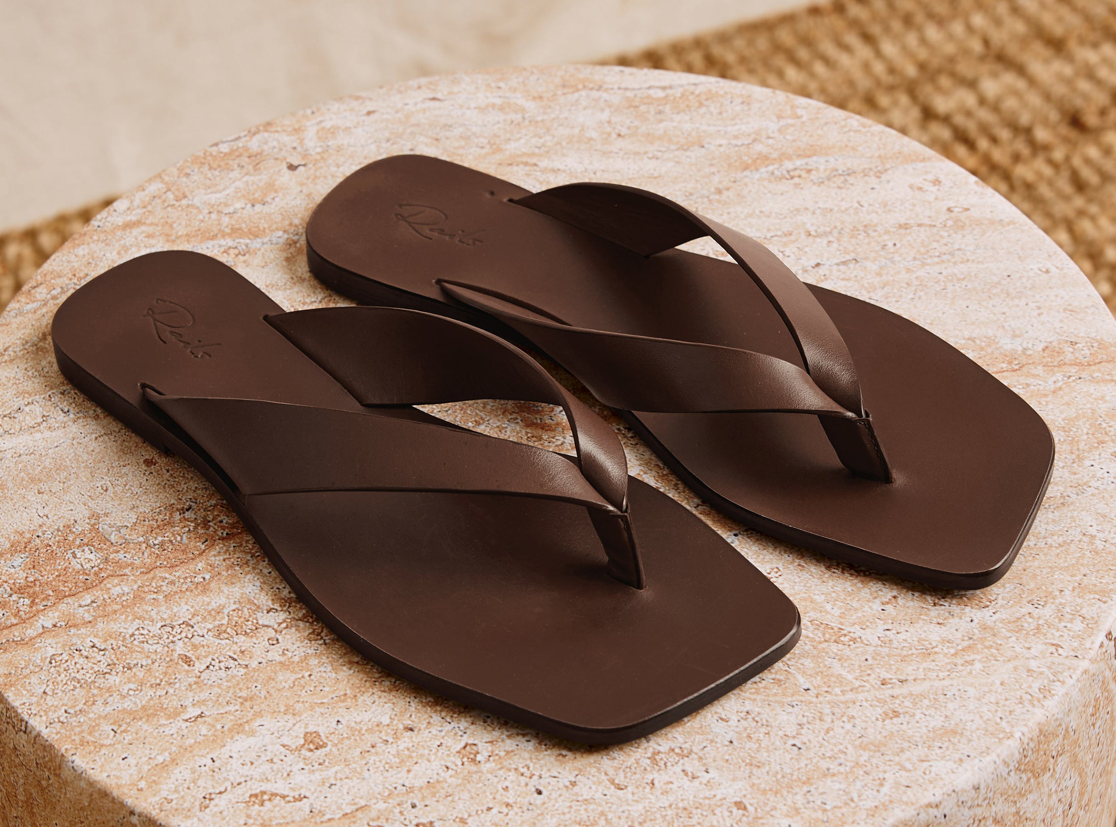 Brown pair of sandals placed on a stone pavement 