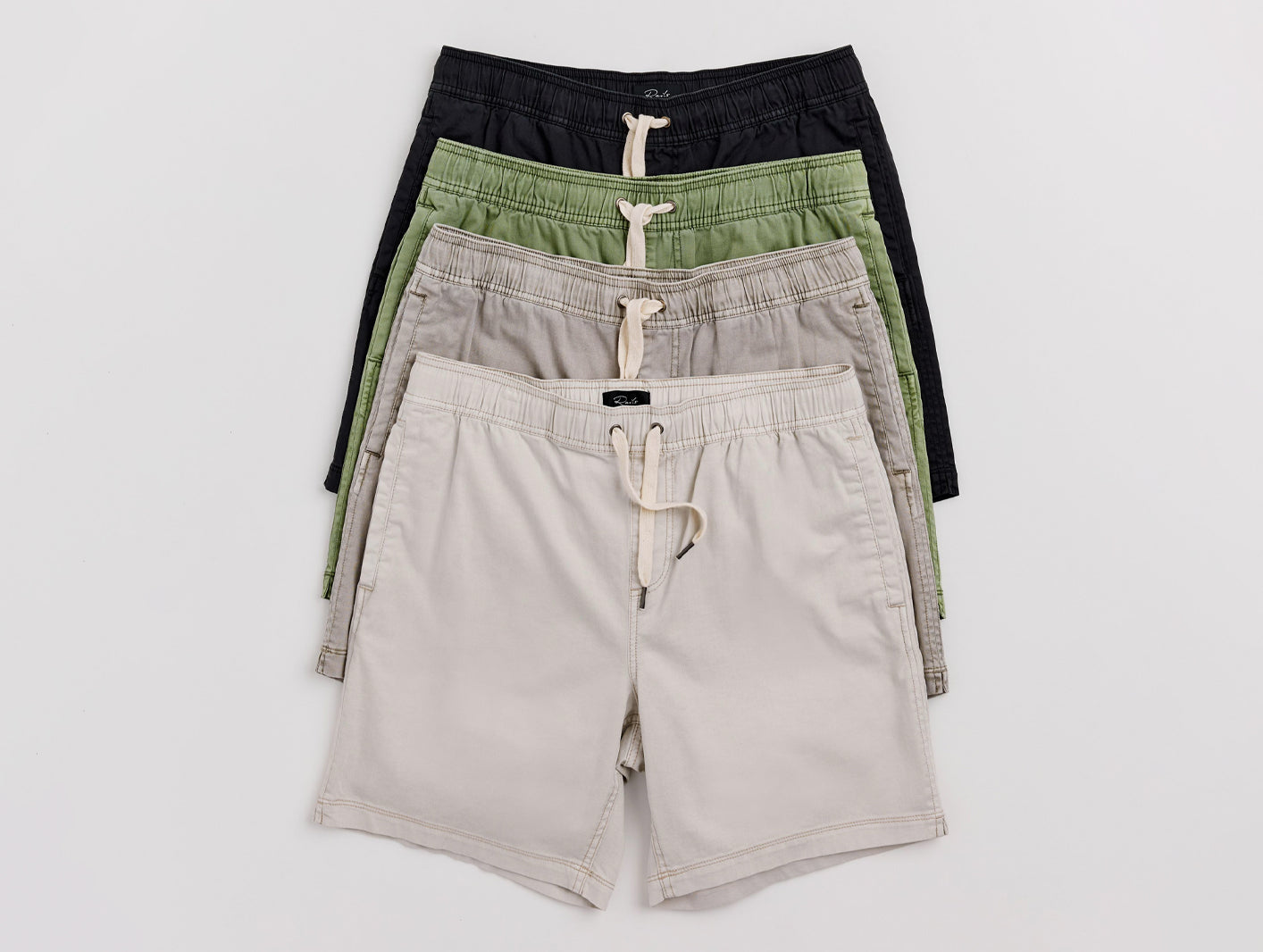 Four pairs of shorts in black, green, and beige on a white background