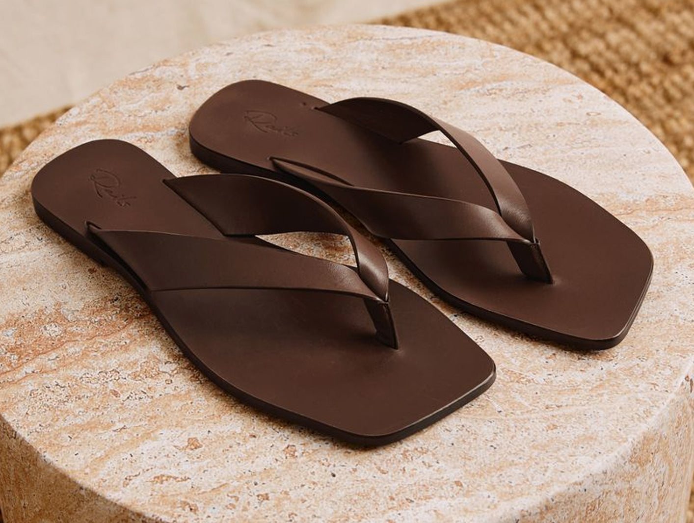 Brown pair of sandals placed on a stone pavement 