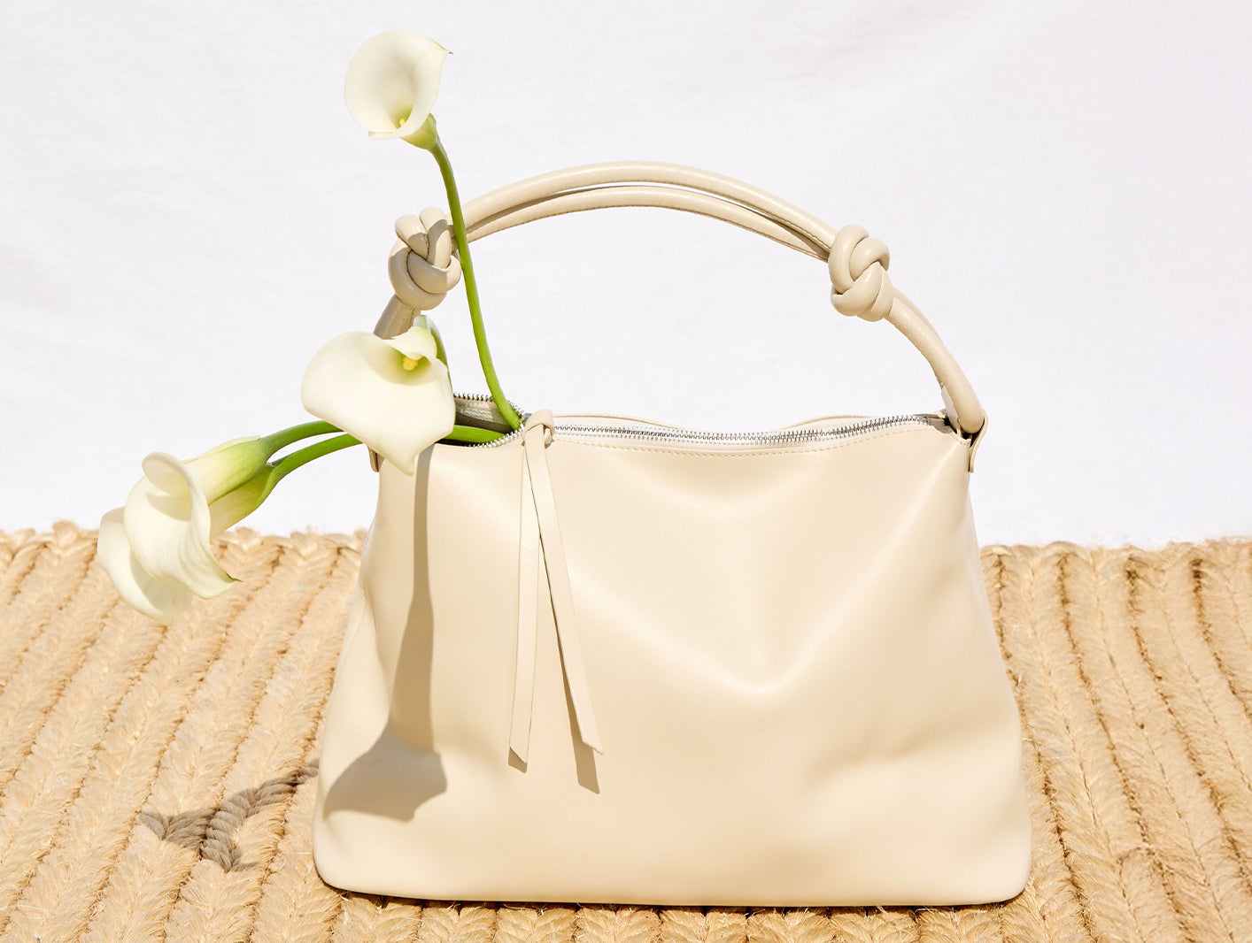 Beige handbag with white flowers on a textured surface
