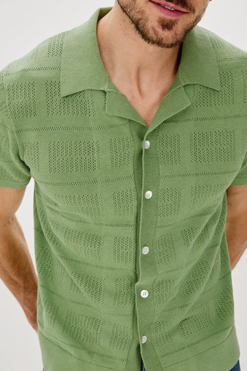 Yates Button Front Knit Shirt with Short Sleeves, a Relaxed Collar and Lapel, Ribbed Sleeve Cuff, Collar, Hem and Front Button Placket in Cream Colorway. Front Detail View Shown on Model.