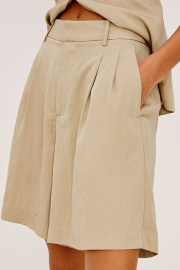Zamora High-Waisted Bermuda Short in Linen Viscose With Front Pleats and Side Pockets in Almond Colorway - Lower Body Side Close Up View Featured on Model
