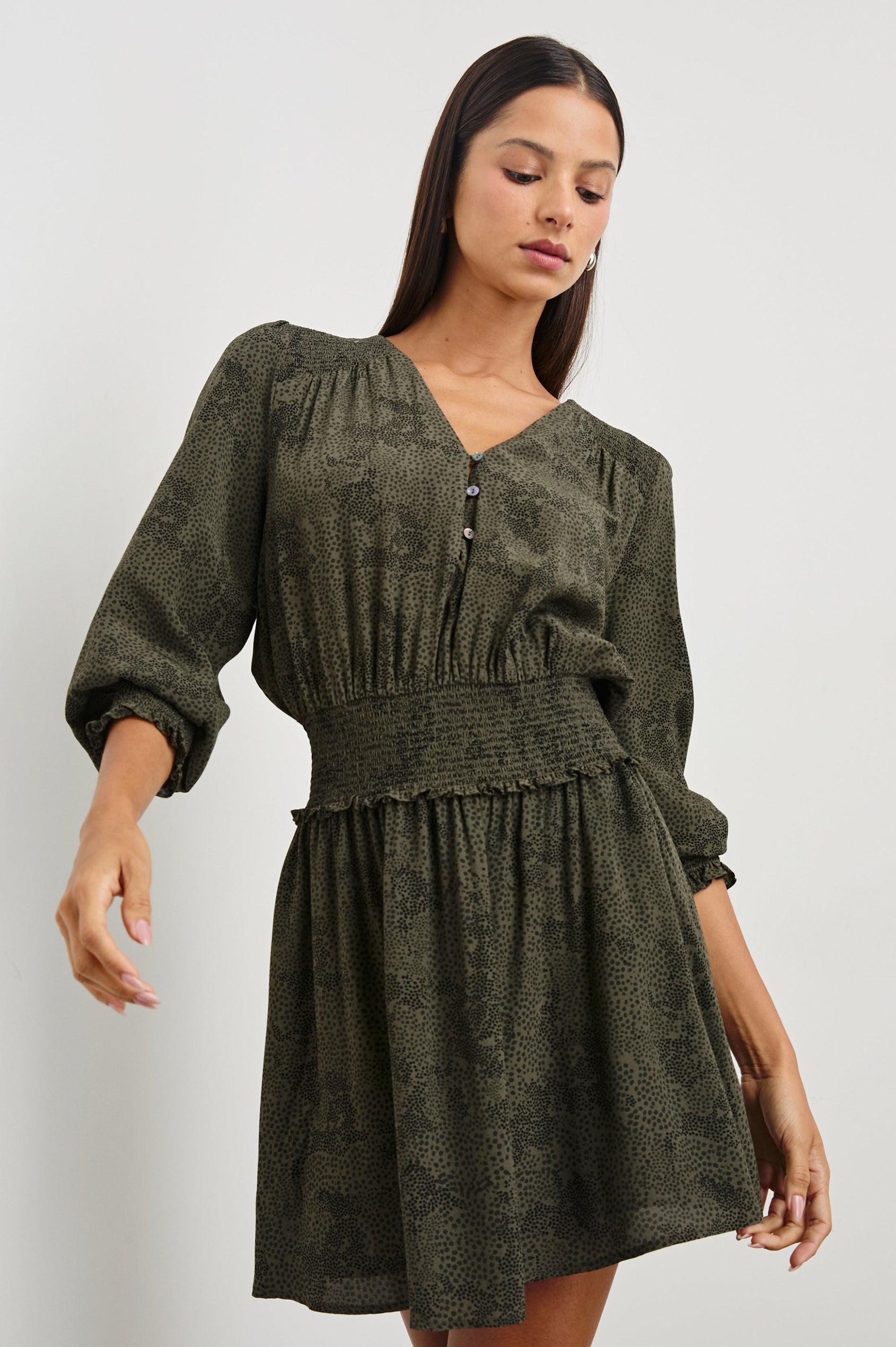 Zana Long-Sleeve Mini Dress with a V Neck, Smocked Cuffs and Waist, and Buttons Down the Bodice in Olive Pebble Colorway, an Olive and Black Pattern - Front View Featured on Model
