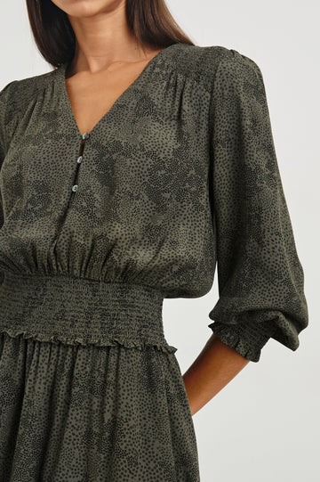 Zana Long-Sleeve Mini Dress with a V Neck, Smocked Cuffs and Waist, and Buttons Down the Bodice in Olive Pebble Colorway, an Olive and Black Pattern - Front View Featured on Model