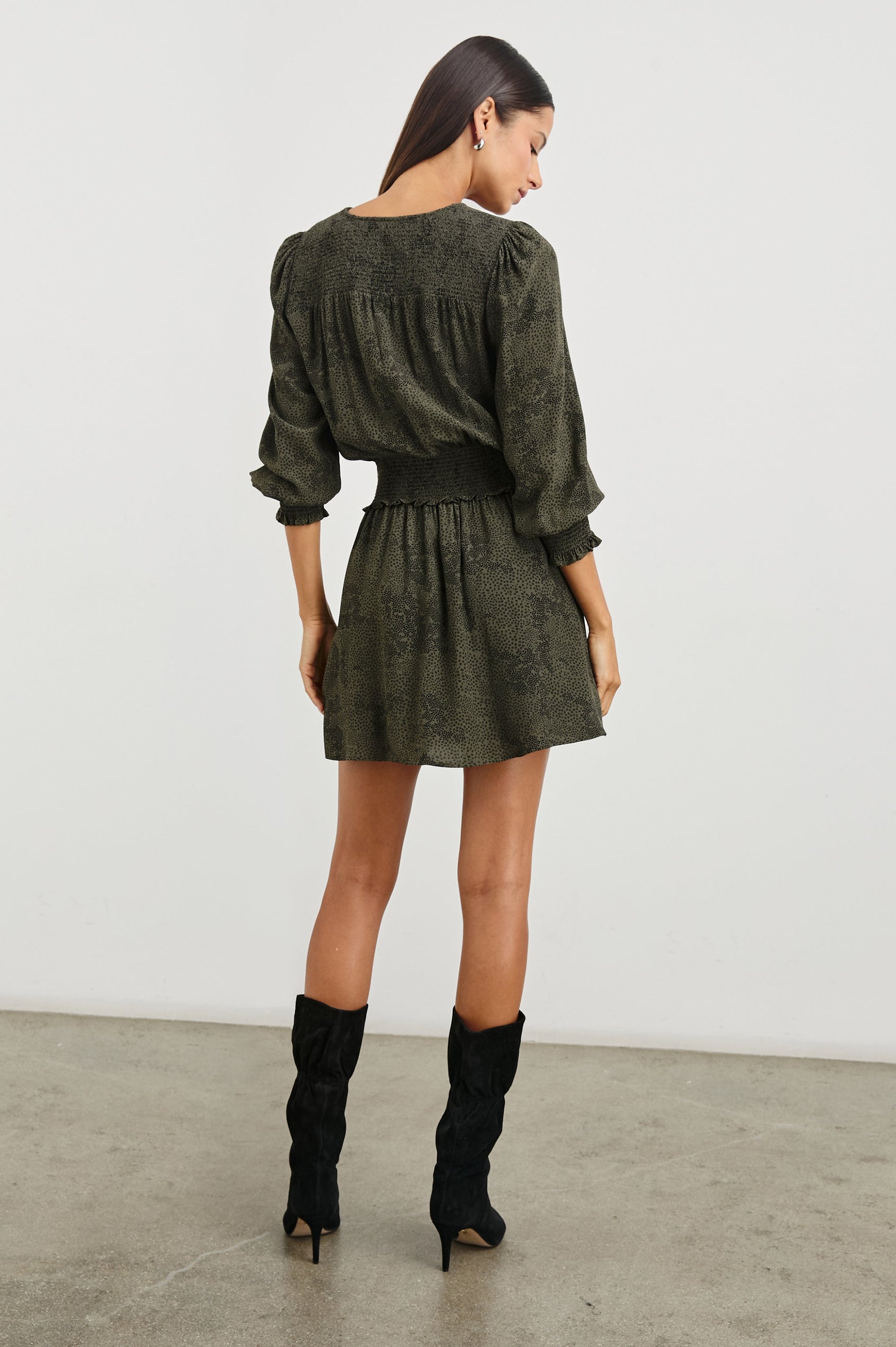 Zana Long-Sleeve Mini Dress with a V Neck, Smocked Cuffs and Waist, and Buttons Down the Bodice in Olive Pebble Colorway, an Olive and Black Pattern - Back  Full Body View Featured on Model