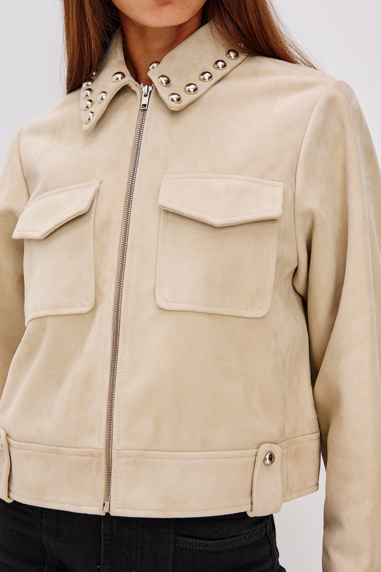 Zeta Boxy Moto Jacket in Suede With Metallic Studs, Collar, Front Zip Closure, Chest Flap Pockets, and Long Sleeves in Taupe Colorway - Close Up Upper Body View Featured on Model