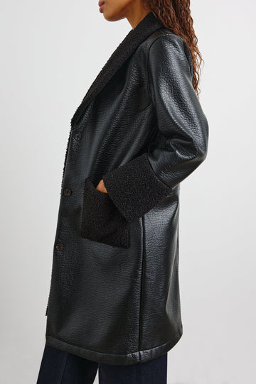 Zodiac Jacket with Button Closure Starting at the Mid-Chest and Two Front Patch Pockets in Black Shearling Colorway, with the Collar, Cuffs and Pockets in Faux Shearling - Side View Featured on Model