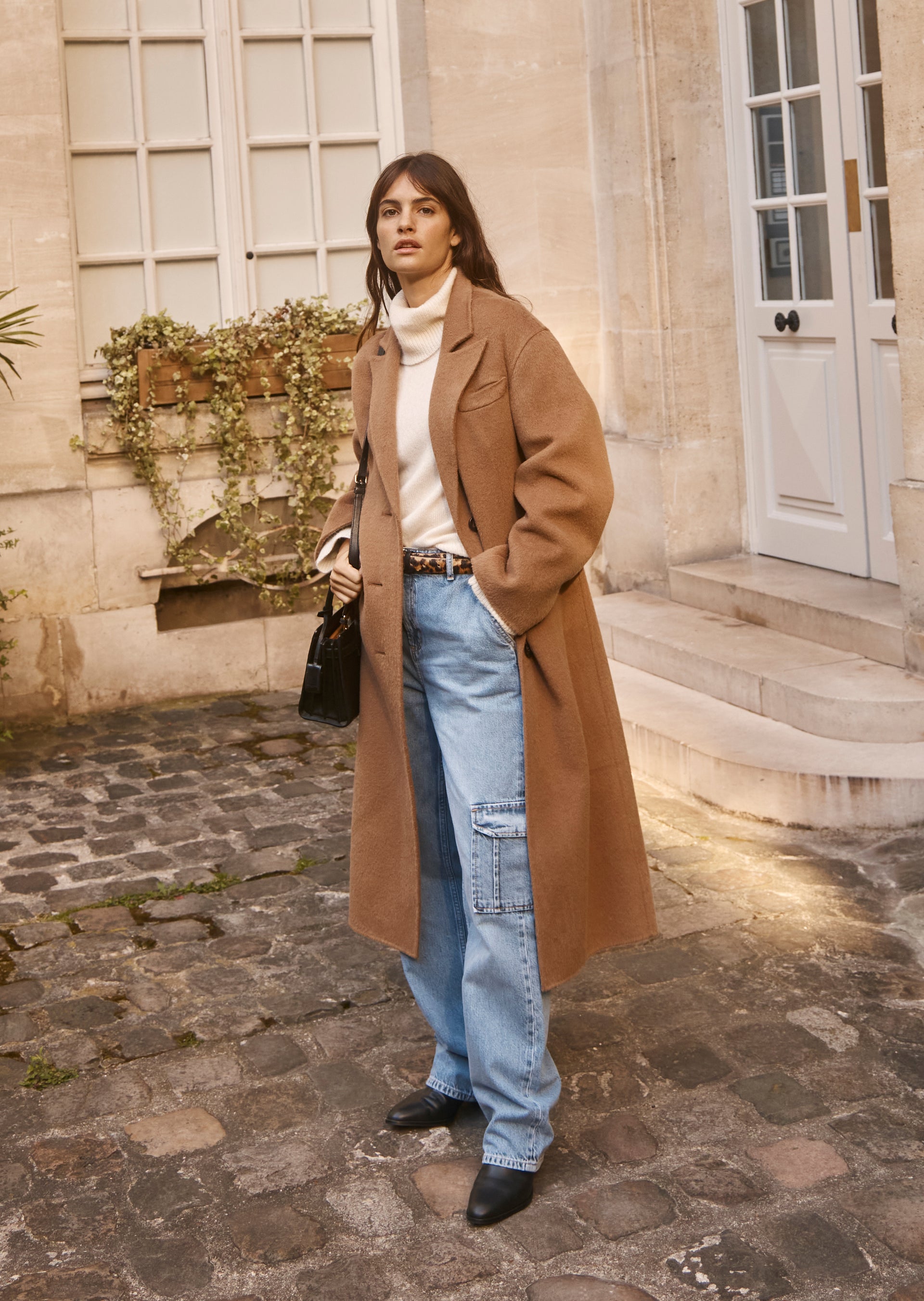 FULL BODY EDITORIAL IMAGE OF MODEL WEARING GALLERY COAT, ESTELLE SWEATER, AND SPEEDWAY CARGO PANT.