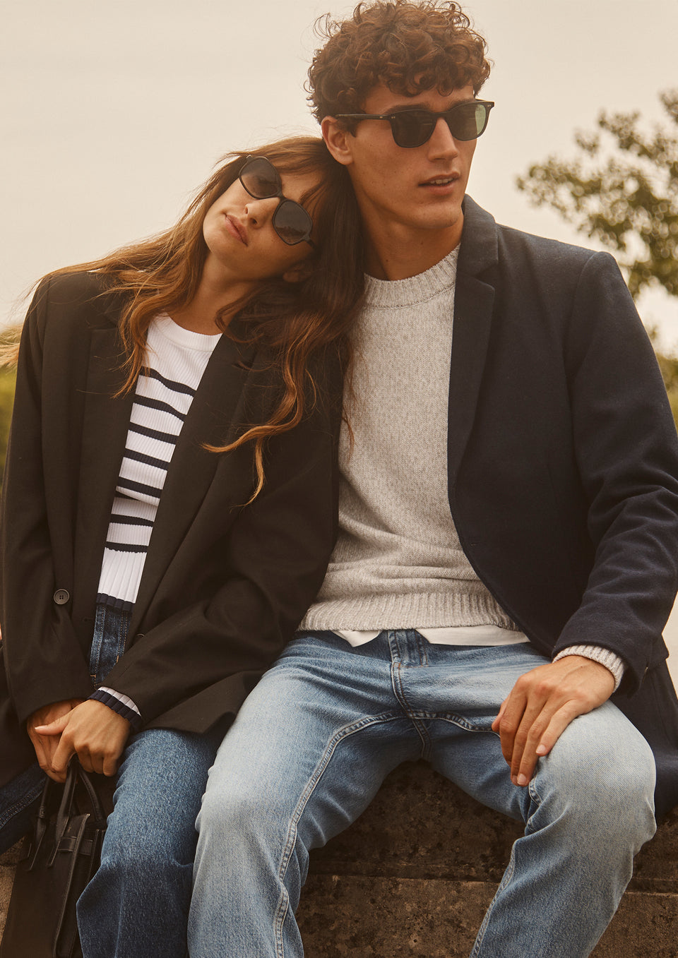 EDITORIAL IMAGE OF TWO MODELS SITTING. FIRST MODEL IS WEARING JAC BLAZER, GEMMA SWEATER, TOPANGA STRAIGH JEAN. SECOND MODEL IS WEARING LARK COAT, DONOVAN SWEATER, AND CLAYTON SLIM STRAIGHT JEAN.