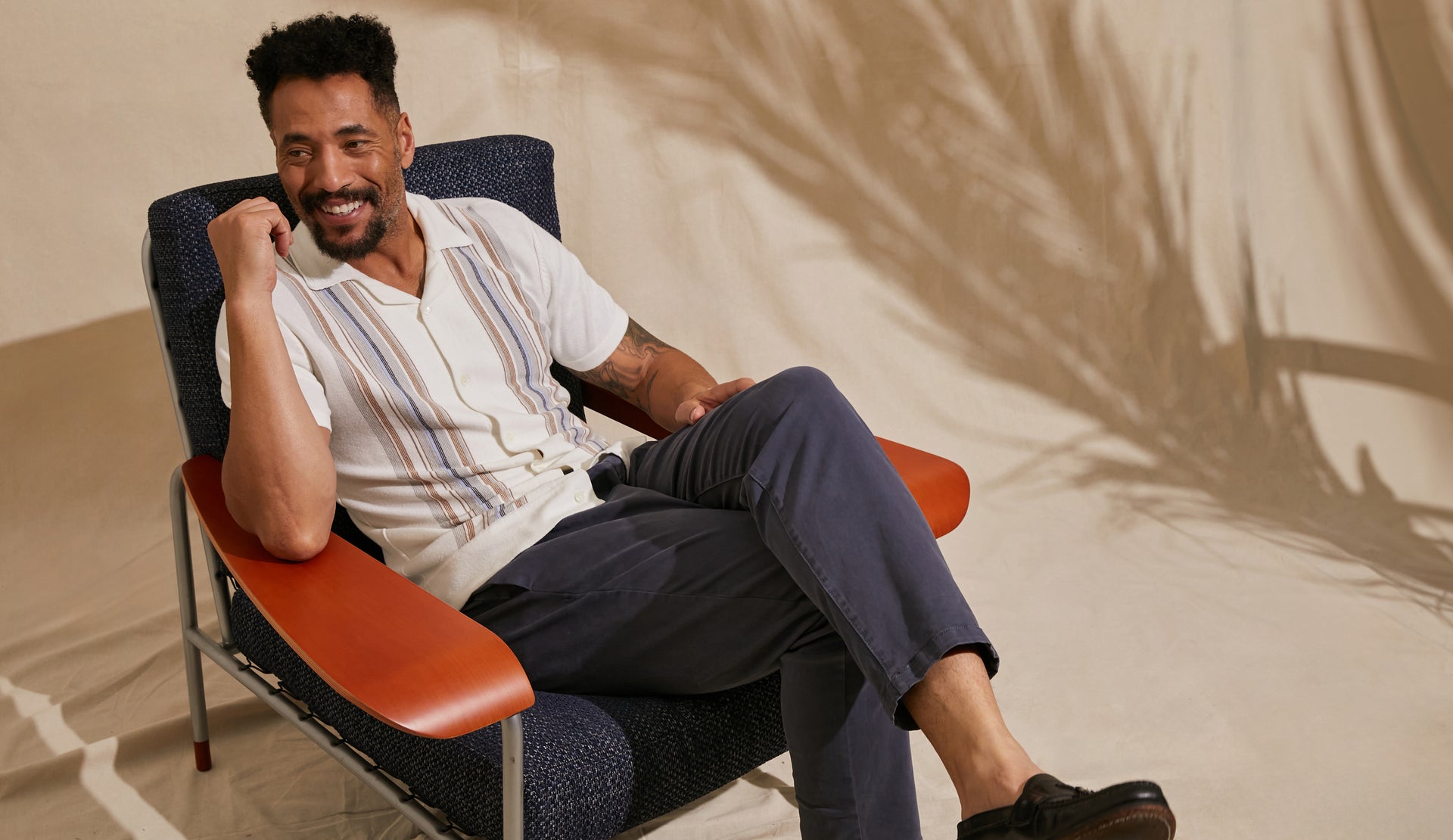 EDITORIAL IMAGE OF MODEL SITTING IN CHAIR WEARING SILAS SHIRT AND JULIAN PANT