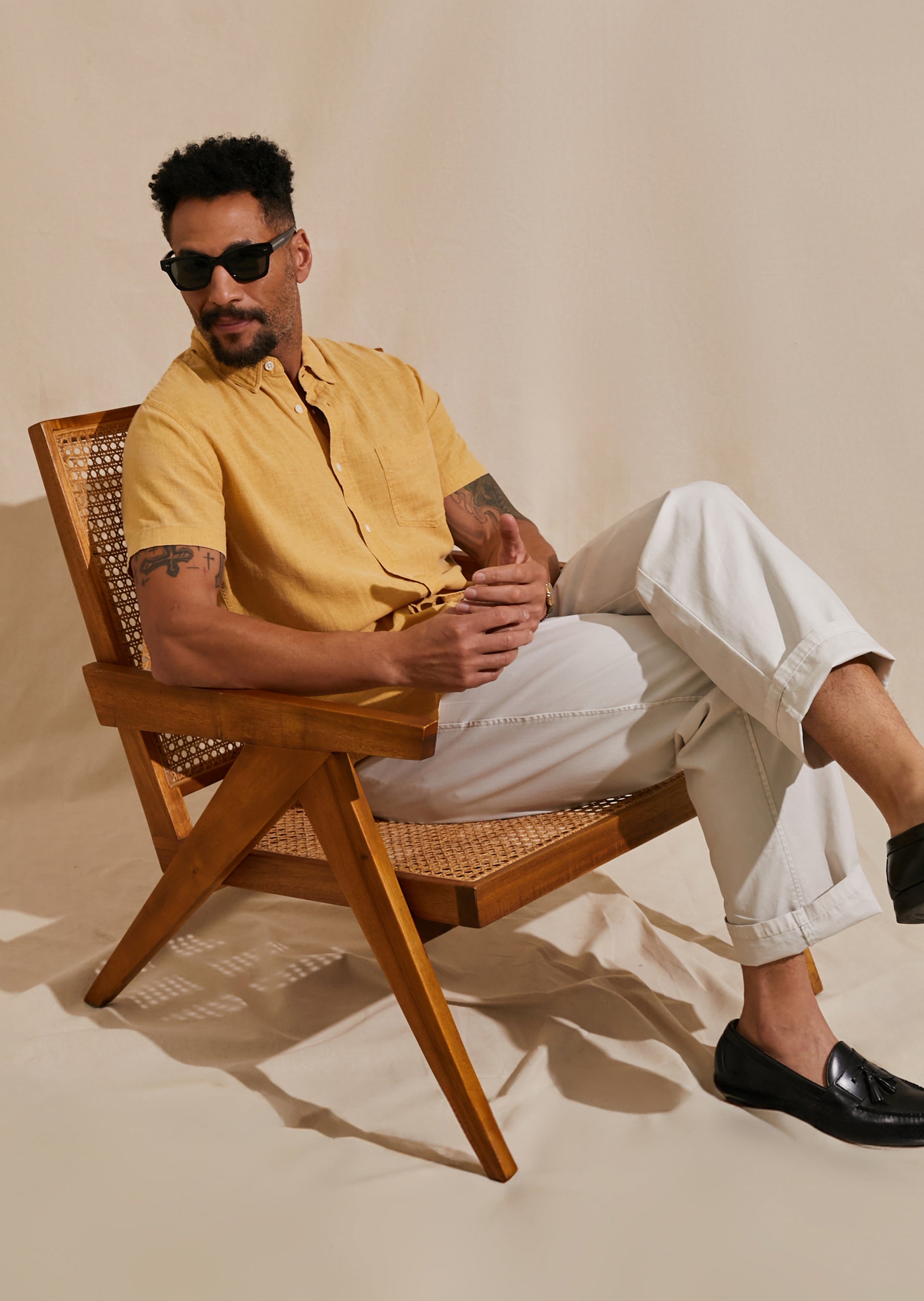 FRONT EDITORIAL IMAGE OF MODEL SITTING IN CHAIR WEARING PAROS SHIRT AND GARRETT PANT