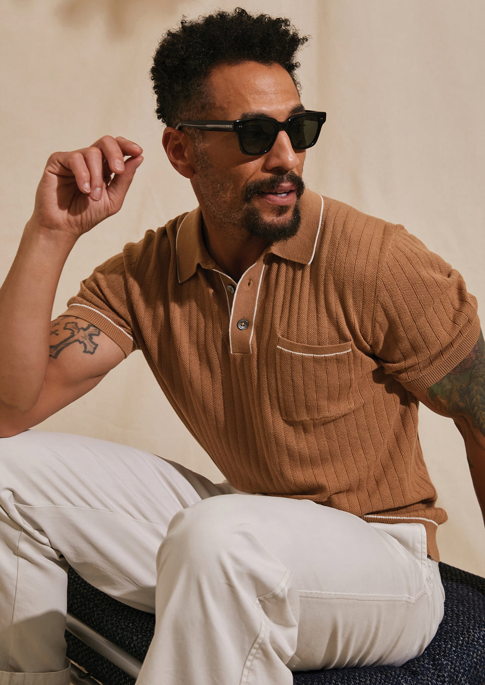 EDITORIAL IMAGE OF MODEL SITTING DOWN WEARING HARDY POLO SHIRT AND GARRETT PANT