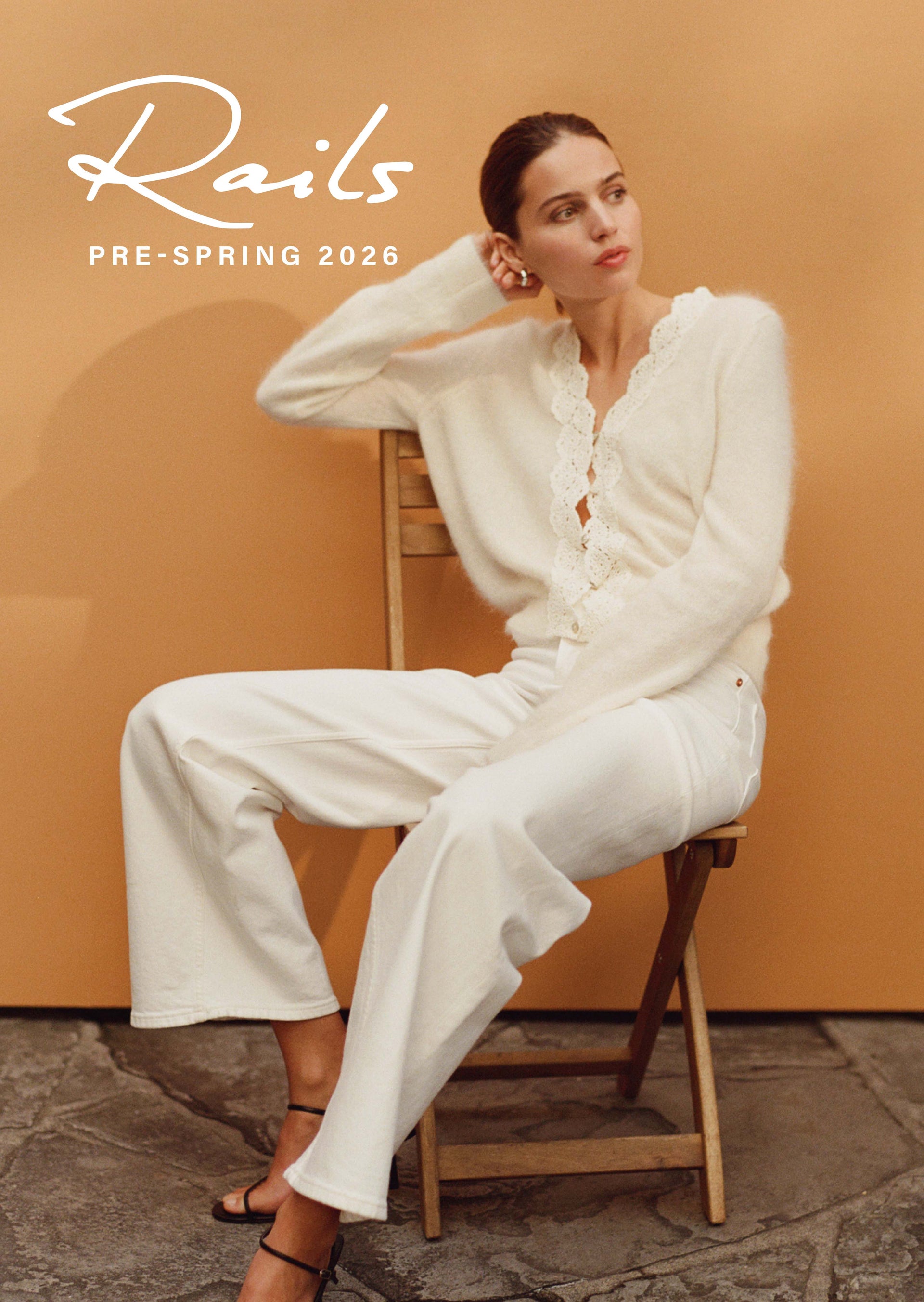 Woman in a white outfit sitting on a chair with 'Rails' branding above.