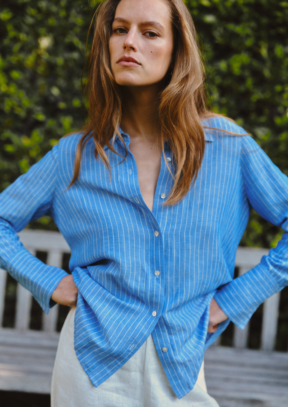 Woman wearing a blue striped shirt with a blurred green background